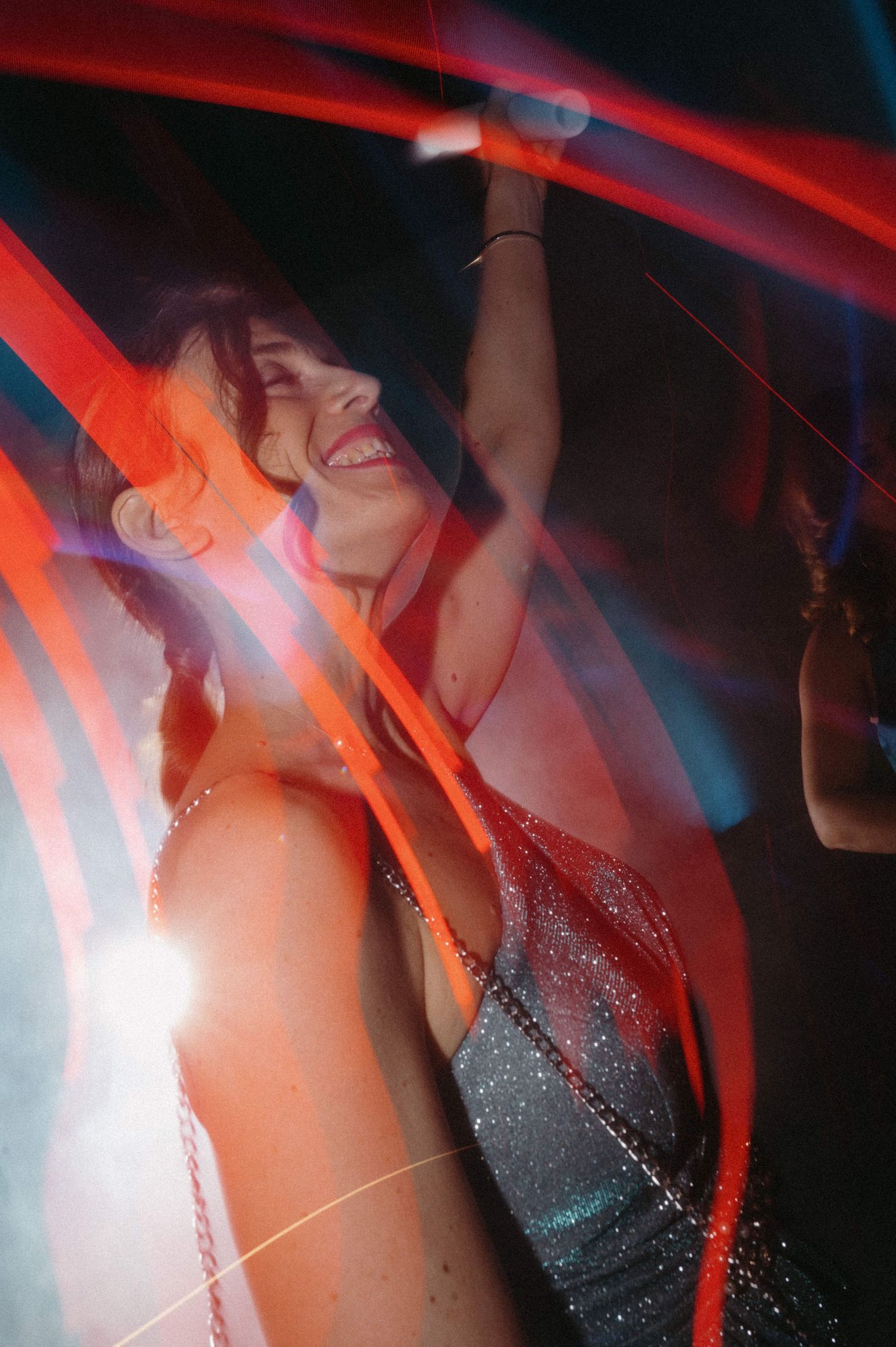 A person dancing at a nightclub with red and blue lighting effects creating a dynamic motion blur atmosphere.