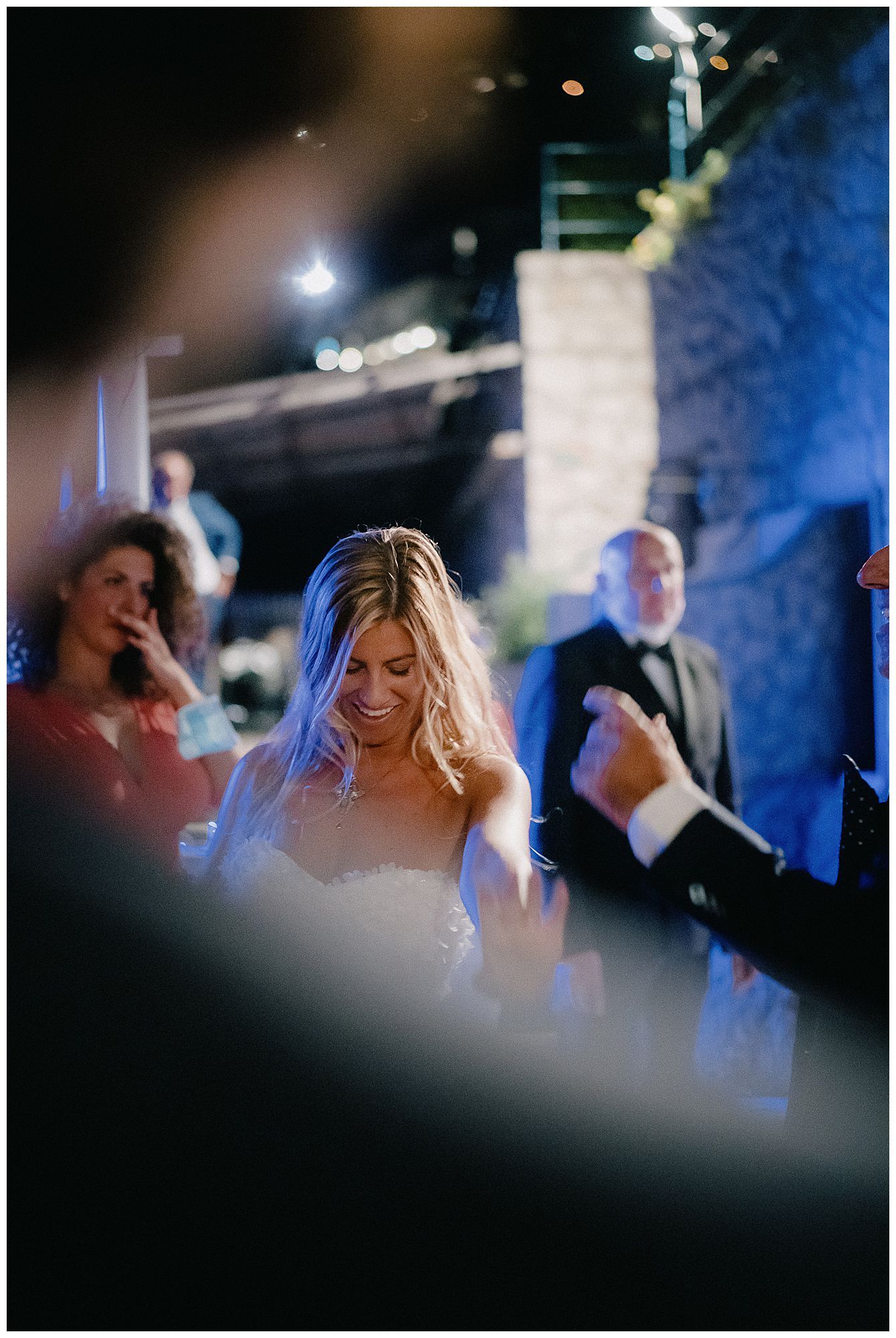 Candid wedding reception scene with guests and soft lighting creating a dreamy atmosphere in a dimly lit venue.