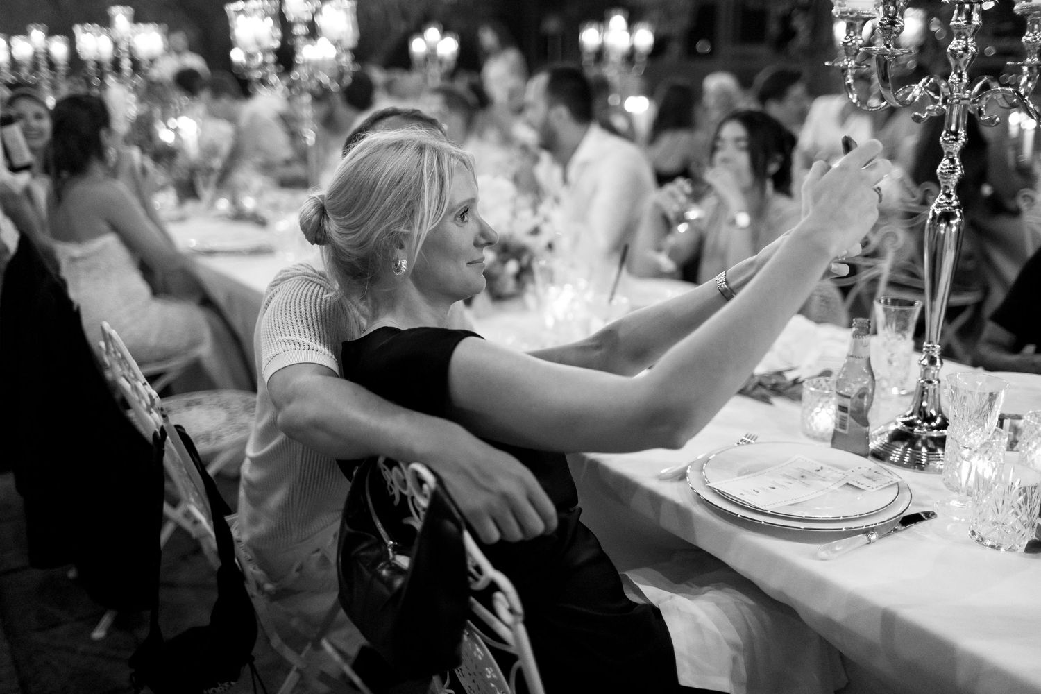 Wedding guests clink champagne glasses together in celebration during an elegant reception dinner.