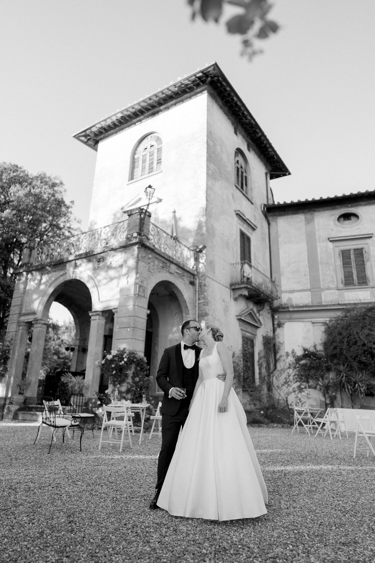 A series of black and white photos showing a bride in a white dress walking through a garden courtyard at different angles.