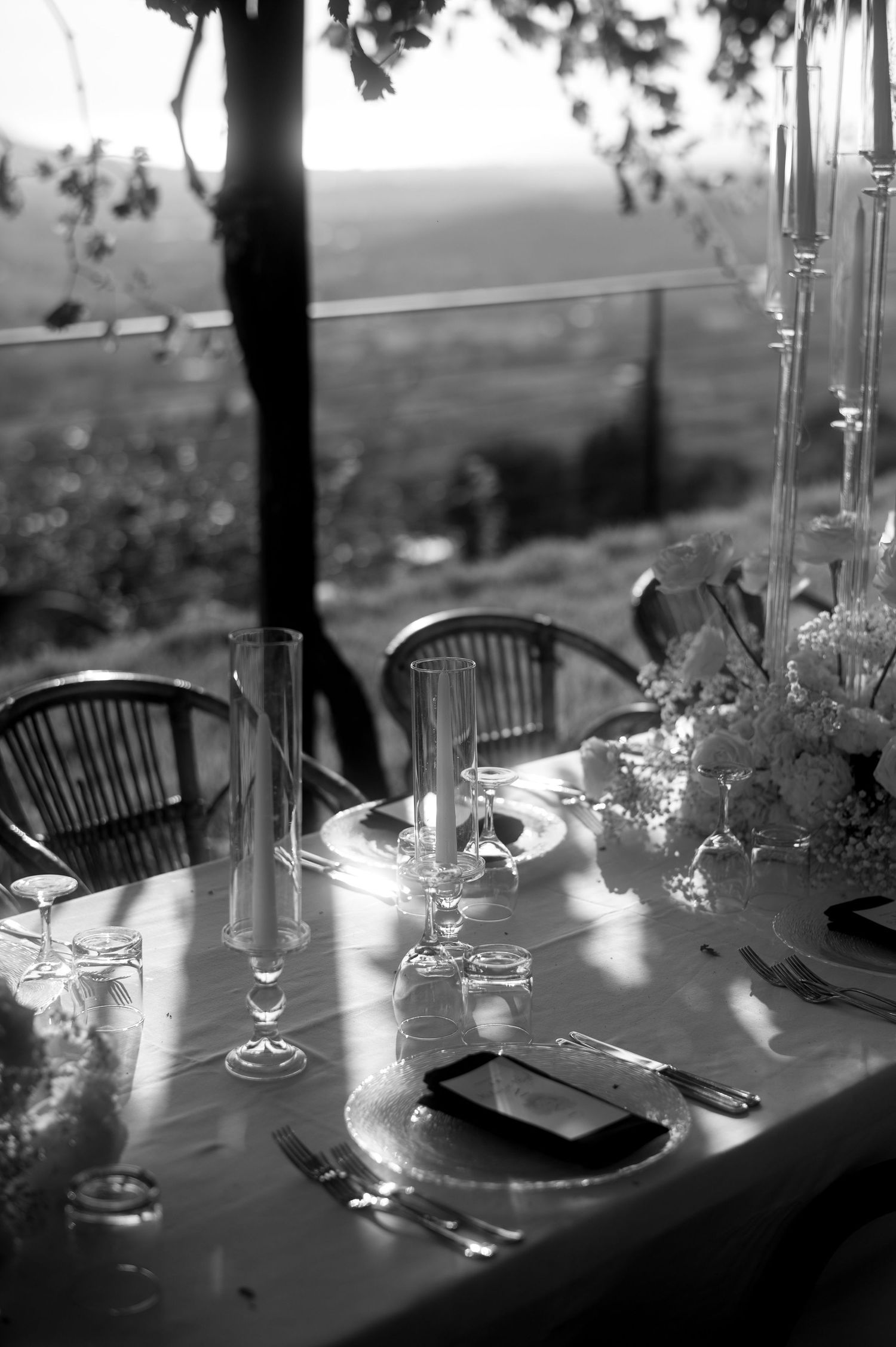 Black and white elegant table setting with wine glasses and place settings overlooking a scenic mountain view.