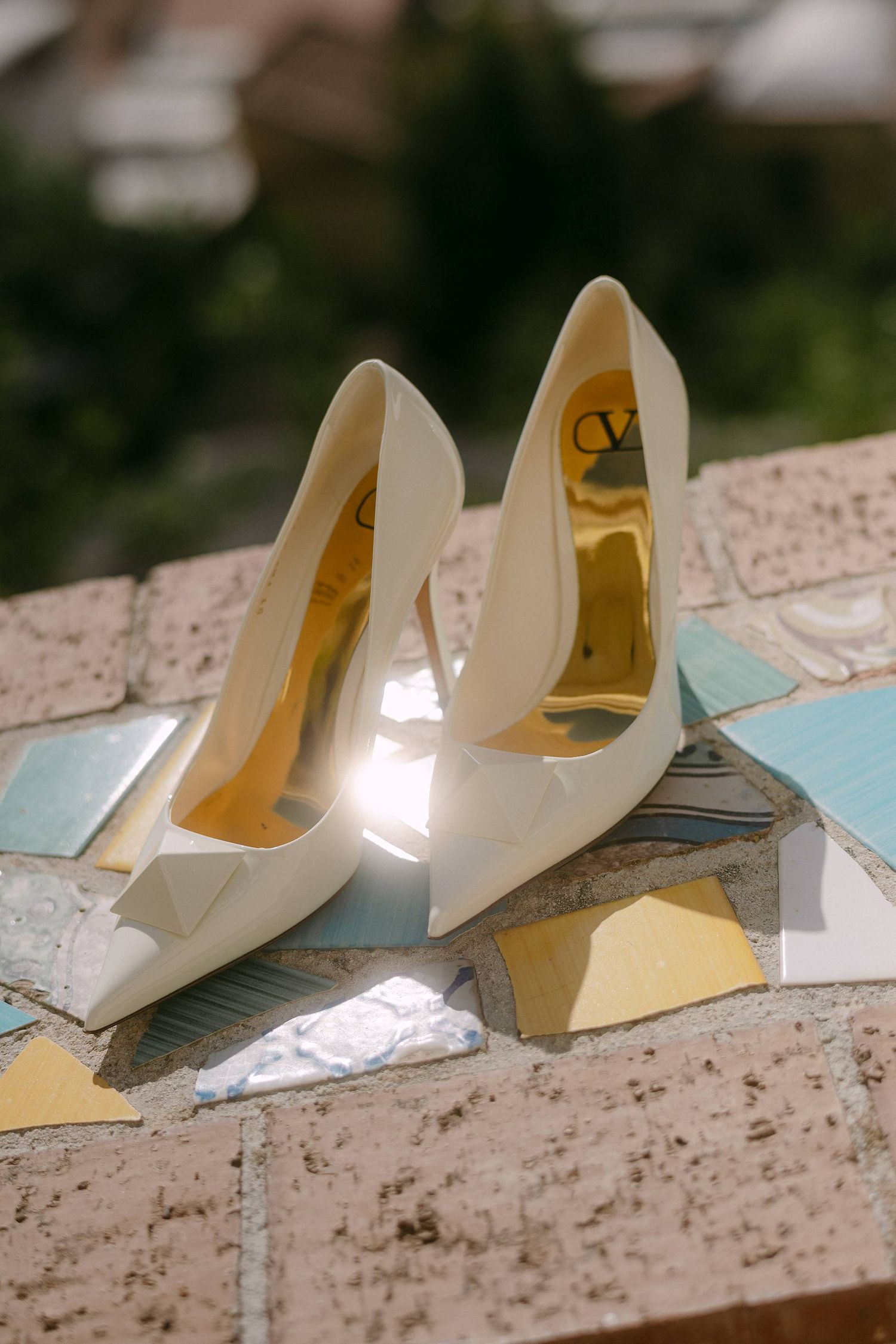 A sequence of white bridal high heel shoes arranged in a row on a textured surface.