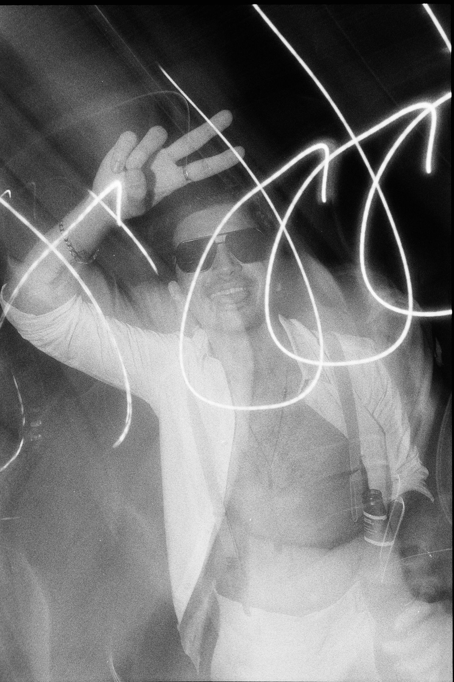 Long exposure black and white photo showing abstract light trails and motion blur creating ghostly white streaks.