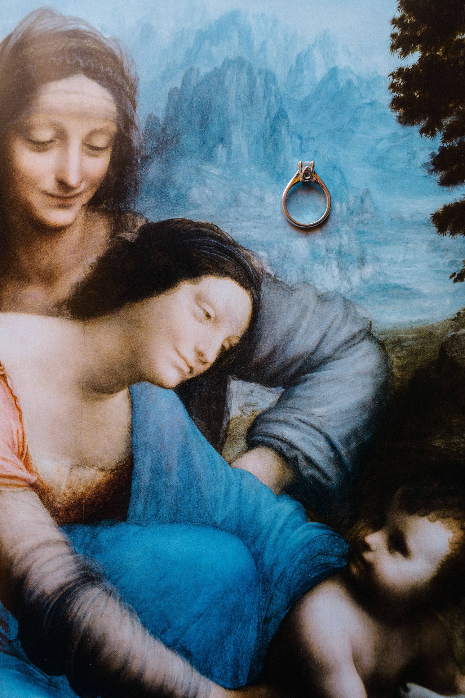 Diamond engagement ring displayed against a Renaissance painting detail, blending classical art with modern jewelry.
