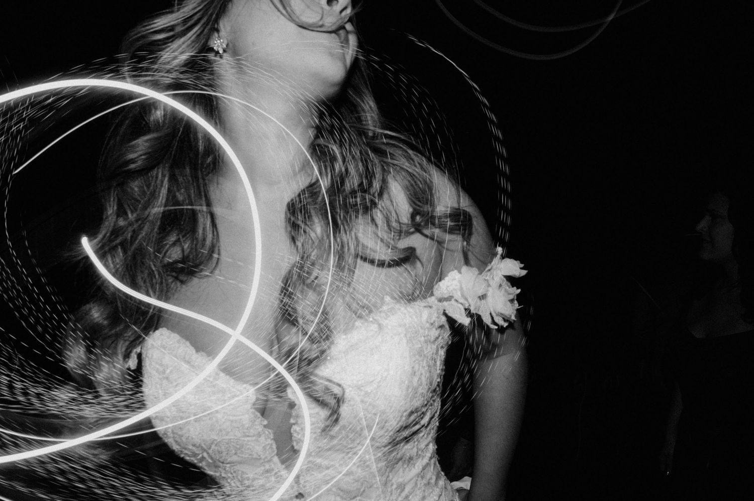 Black and white artistic photograph showing light trails creating abstract swirling patterns in darkness.