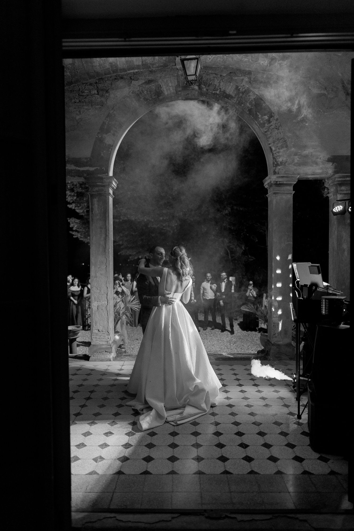 A series of black and white photos showing elegant wedding gowns in a grand room with checkered floor tiles.