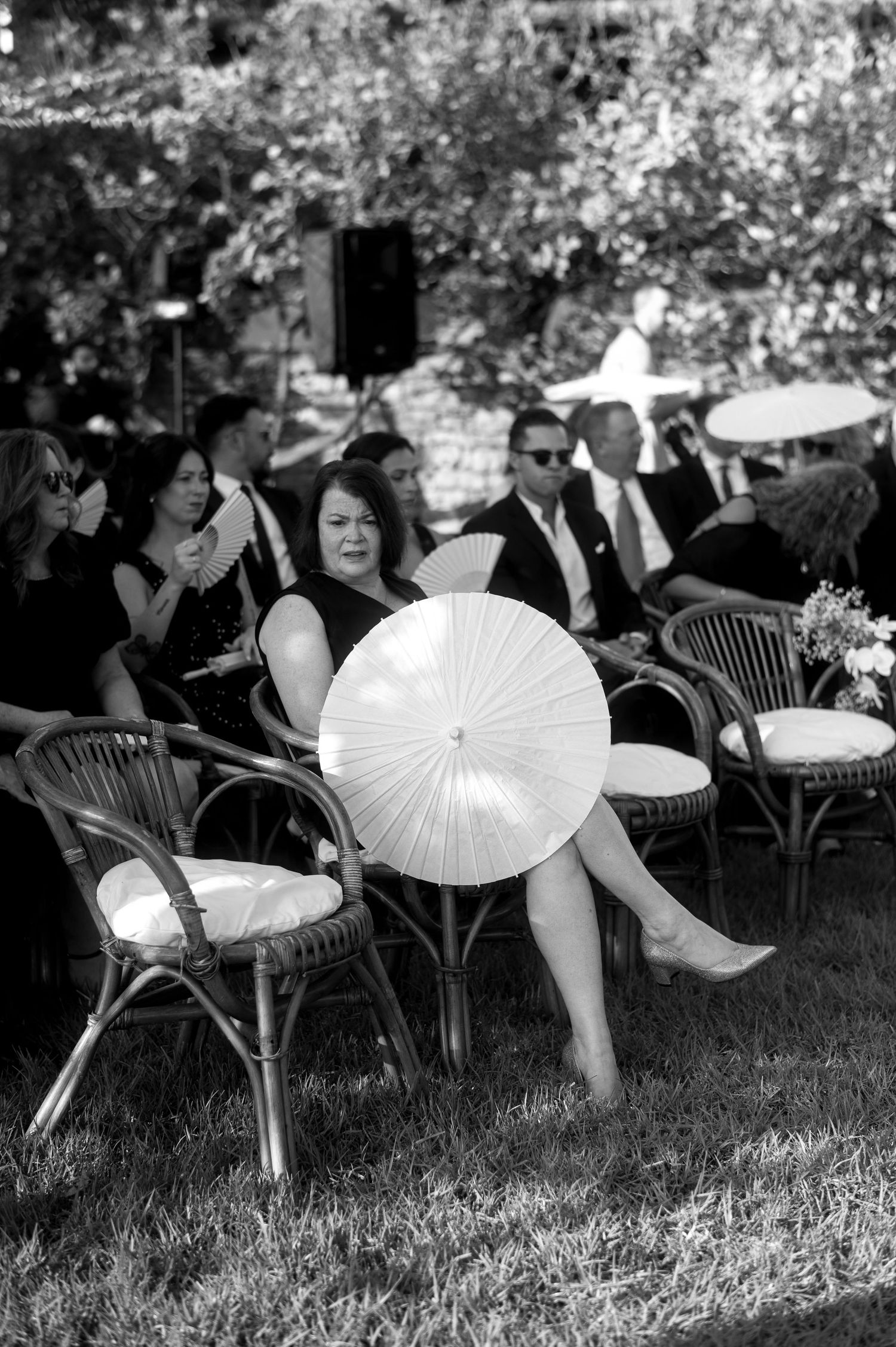Black and white photo series showing people lounging outdoors with decorative white paper parasols at a garden event.