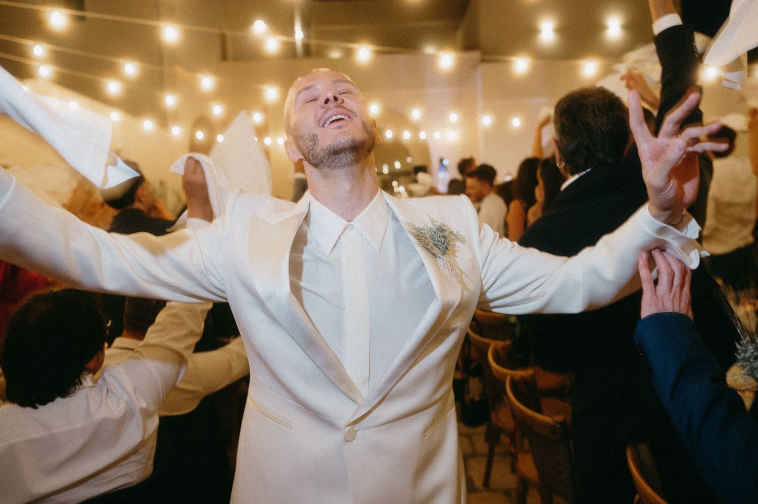 A series of five photos showing people dancing and celebrating at a wedding reception with string lights overhead.