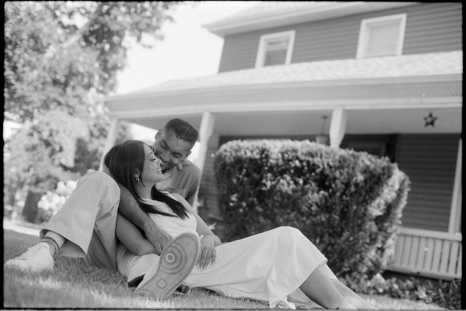 Black and white photo series showing couple in romantic embrace on porch swing during intimate outdoor moment.