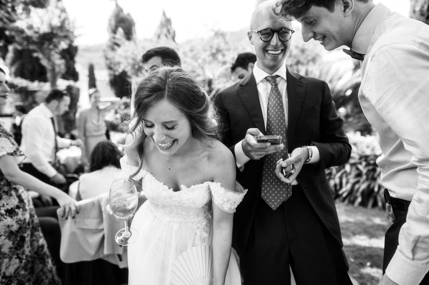 Wedding party enjoying a lighthearted moment outdoors with champagne and laughter.