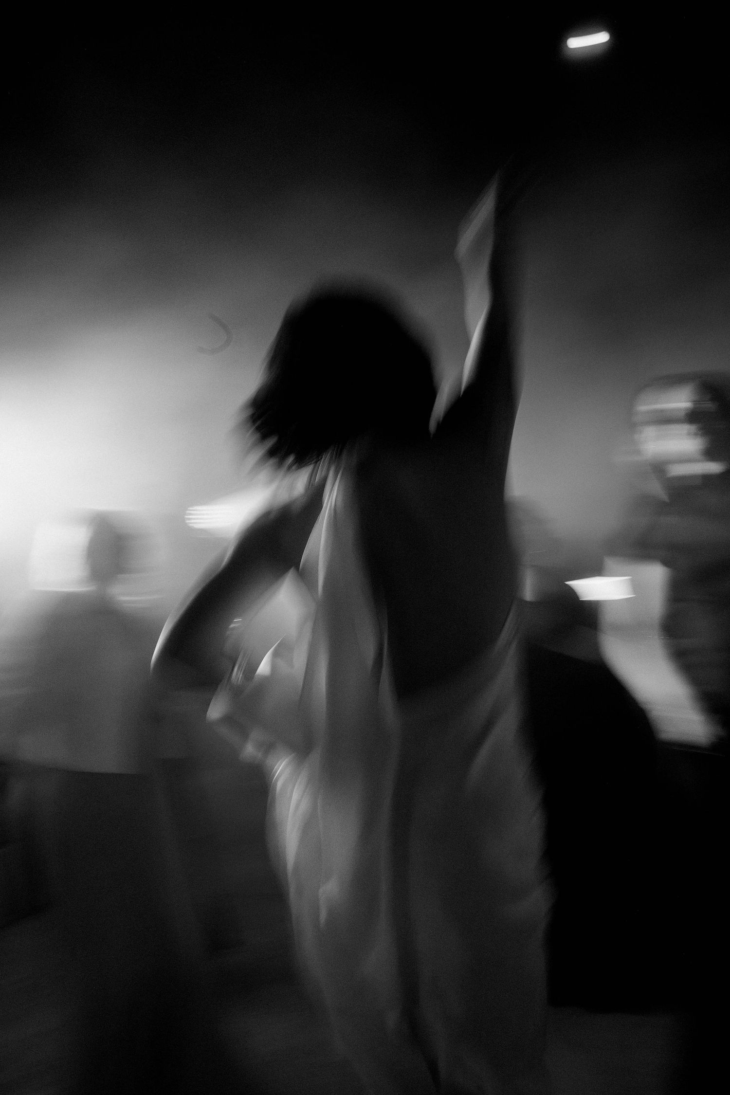 Blurred black and white motion shots of silhouettes dancing in a dark nightclub atmosphere.