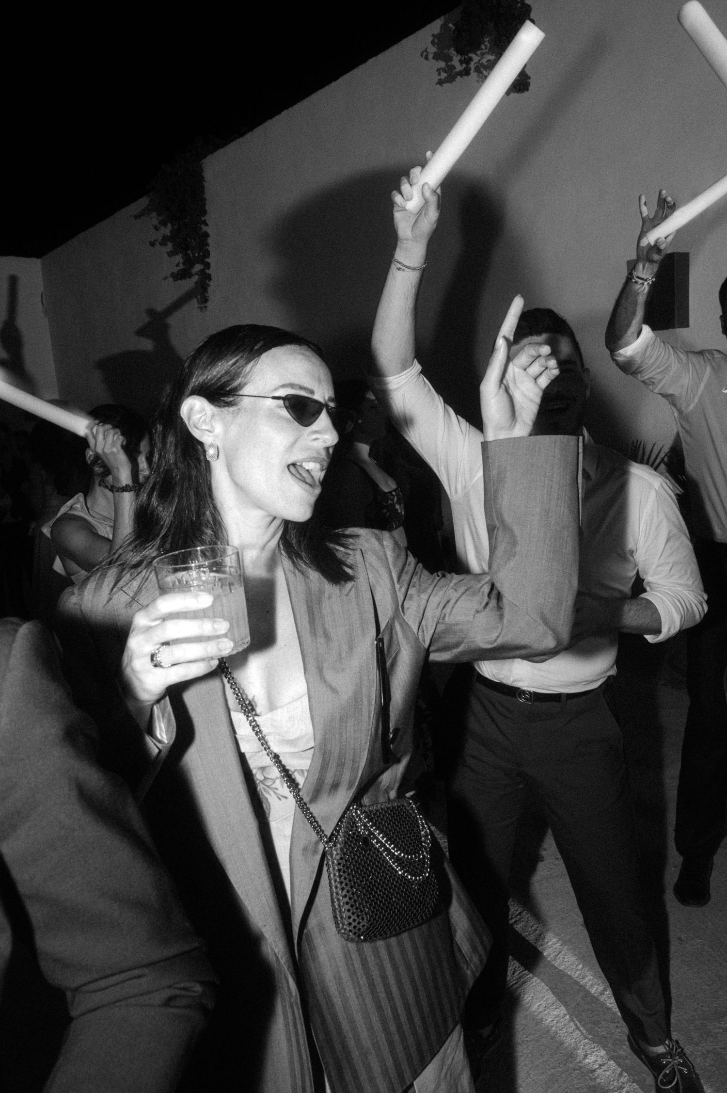 Black and white photos show people dancing and having fun at a party with raised arms and energetic movements.