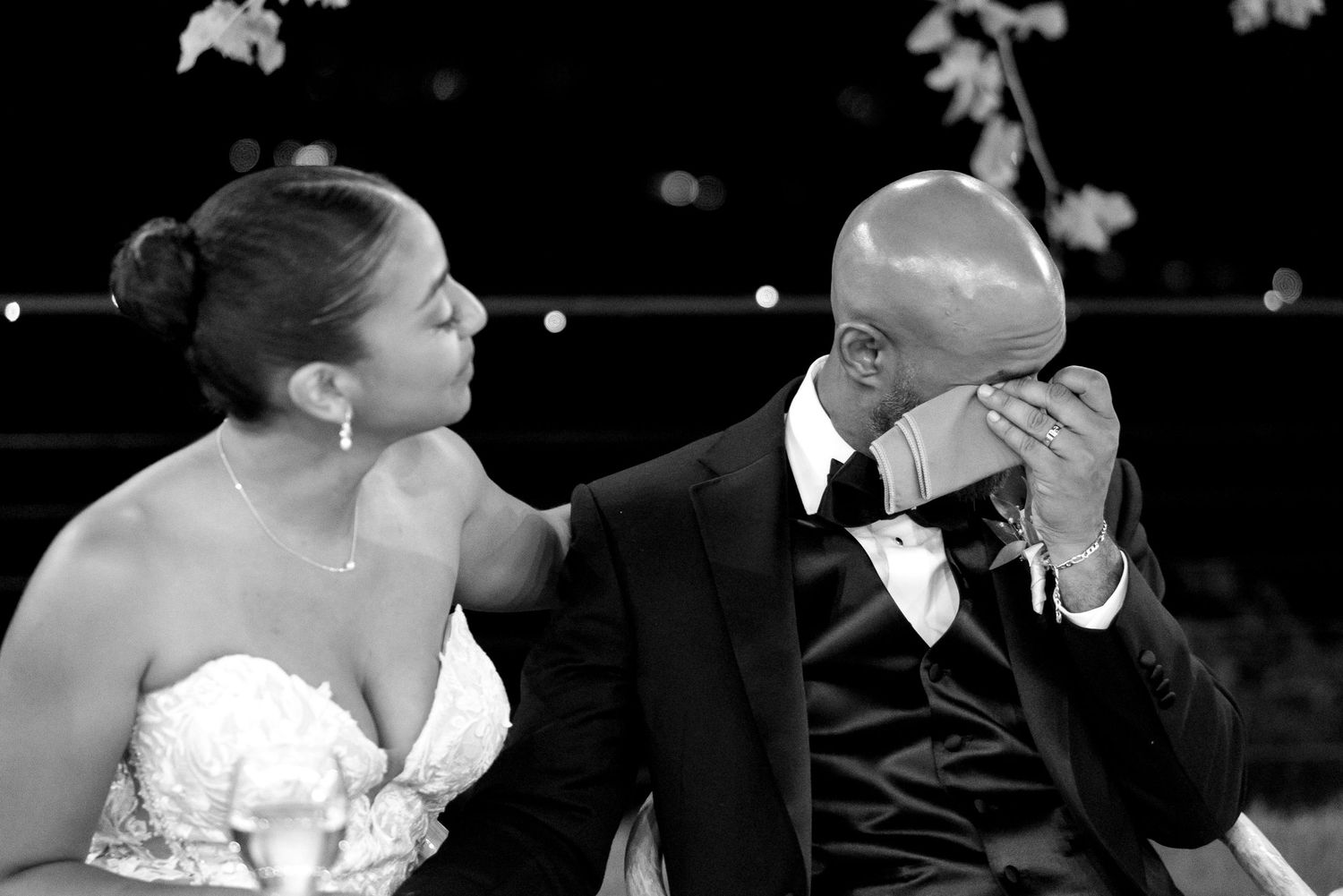 A couple shares a romantic kiss during a wedding ceremony while wearing formal attire.