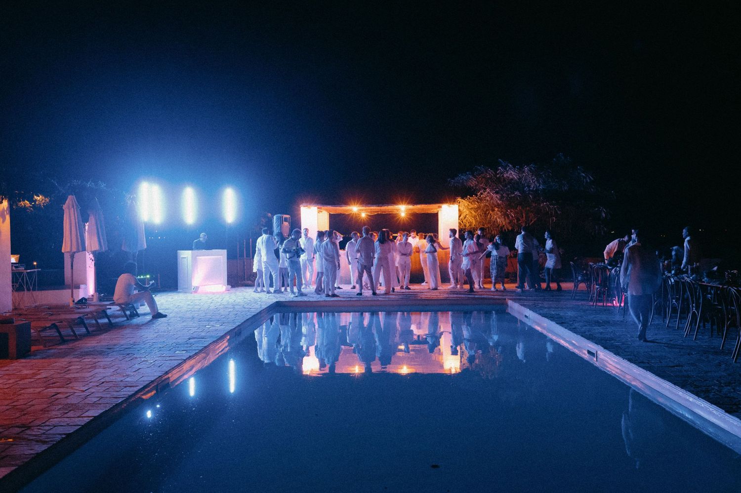 Illuminated swimming pool at night with blue lighting creating a tranquil atmosphere.