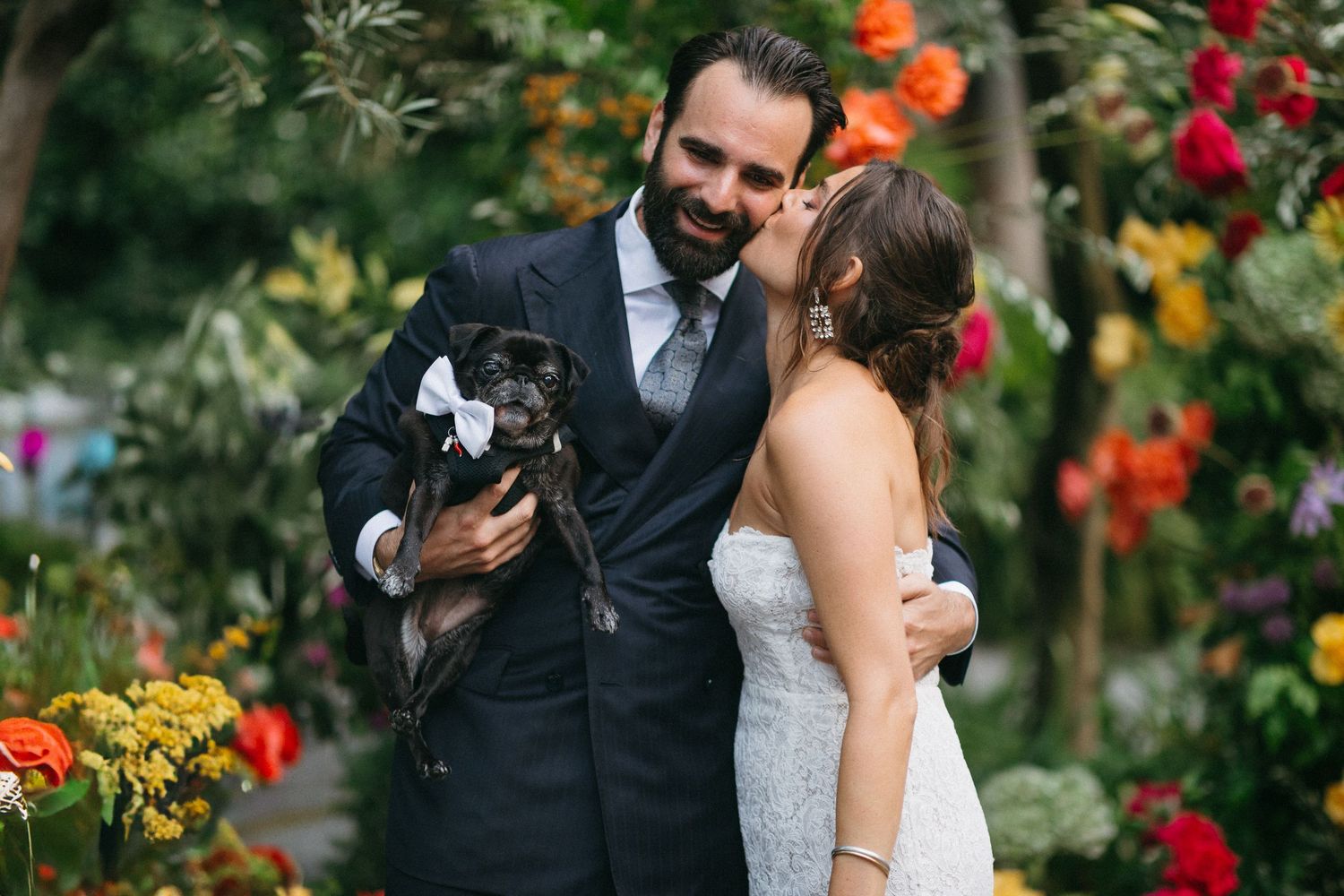 Newlyweds share intimate moments surrounded by vibrant flowers in a lush garden setting during their wedding celebration.