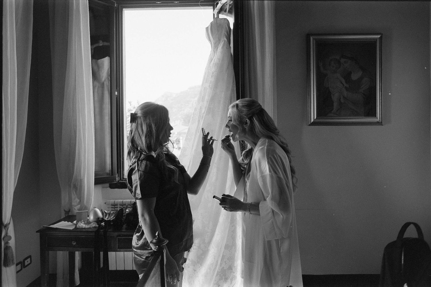 A series of black and white wedding preparation photos showing dress details and silhouettes in a bridal suite.