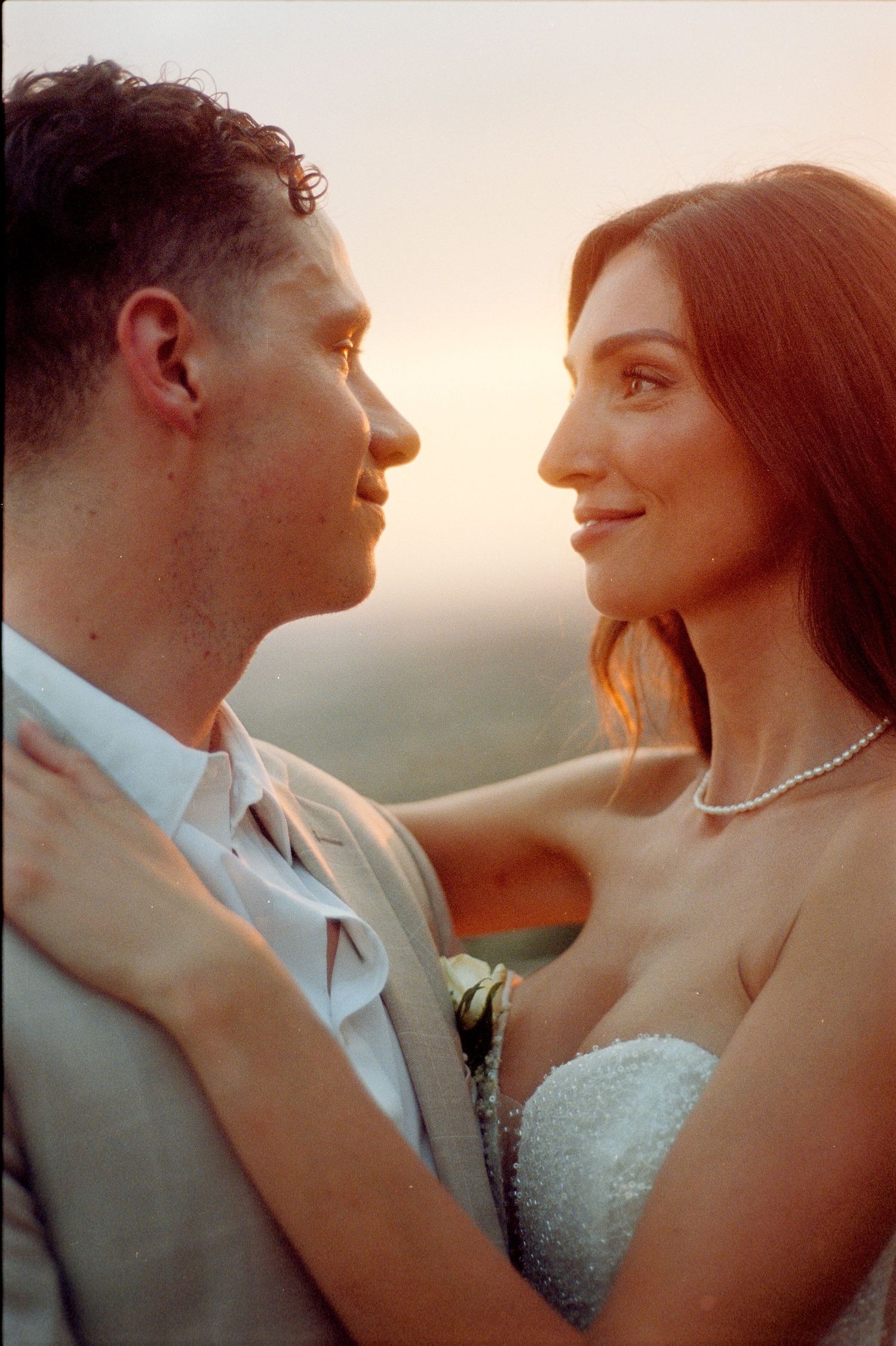 Romantic sunset portrait of a couple in wedding attire sharing an intimate moment during their golden hour photoshoot.