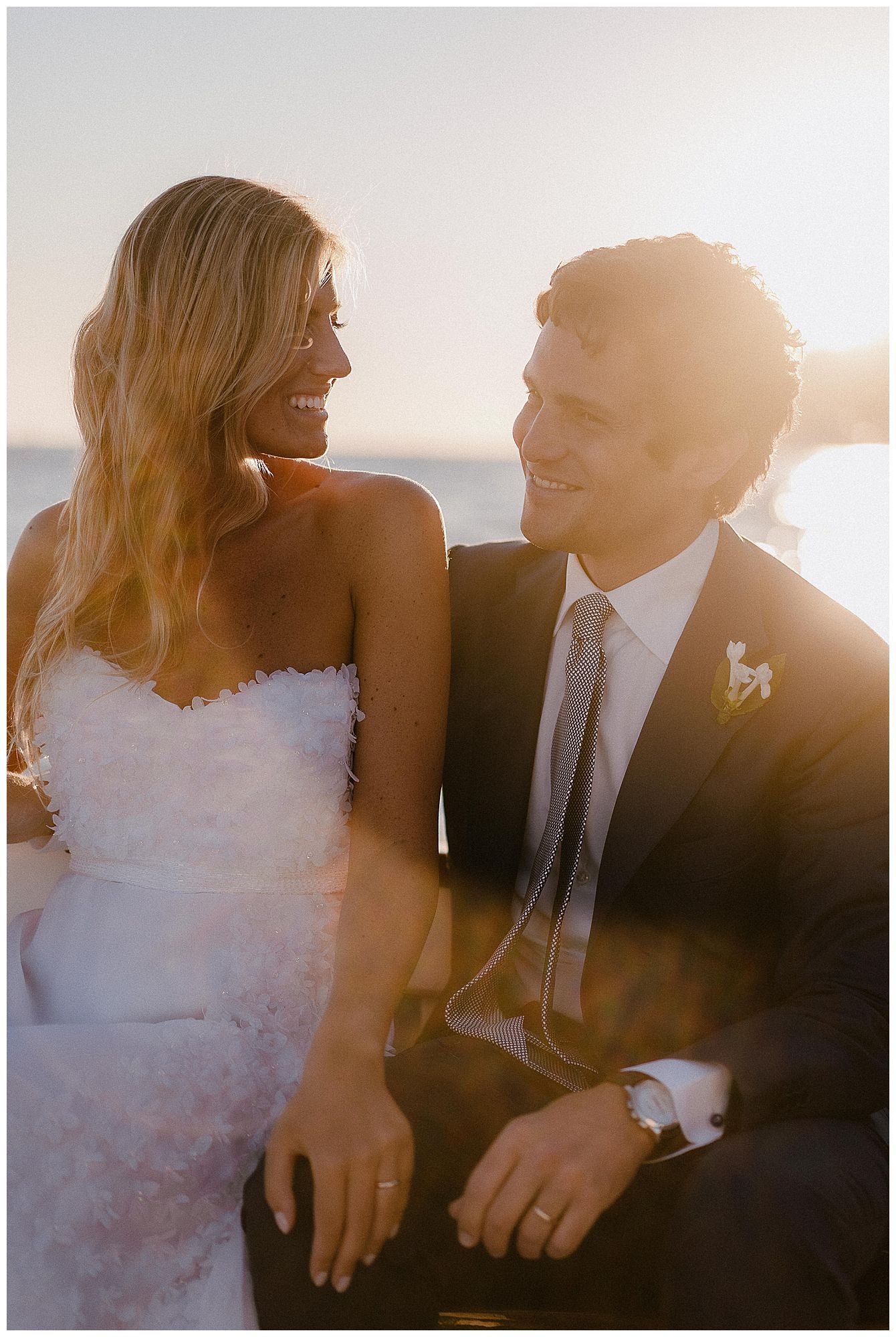 A romantic wedding portrait of a couple sharing an intimate moment at sunset with beautiful golden backlighting.