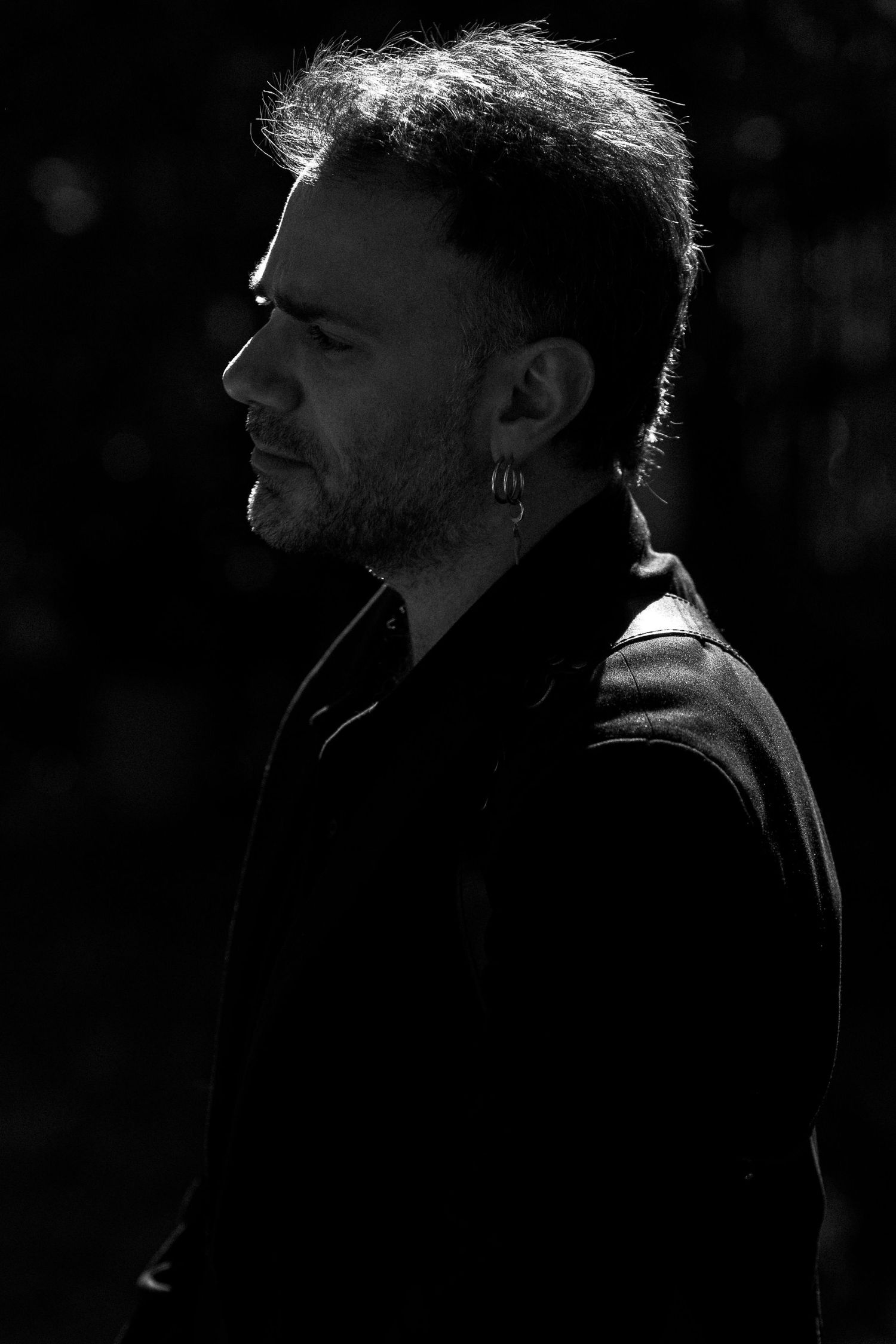 A dramatic black and white profile silhouette portrait showing a shadowy figure against a dark background.