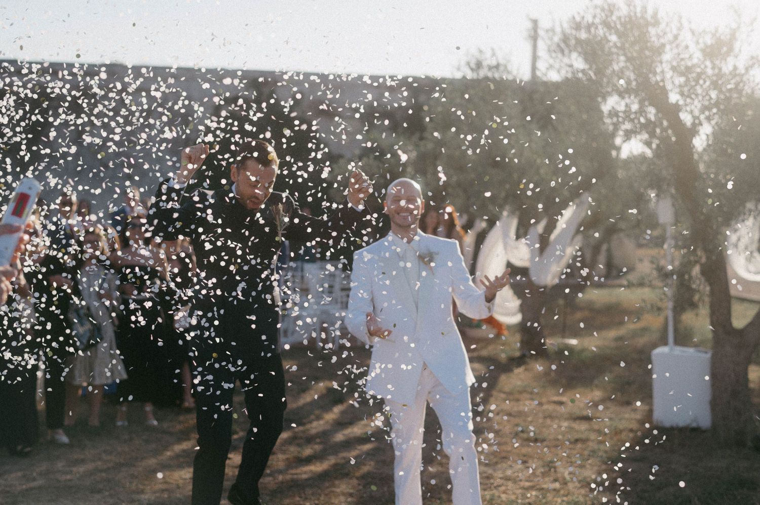 Couple celebrates with confetti during a romantic sunset engagement photo session in an orchard.