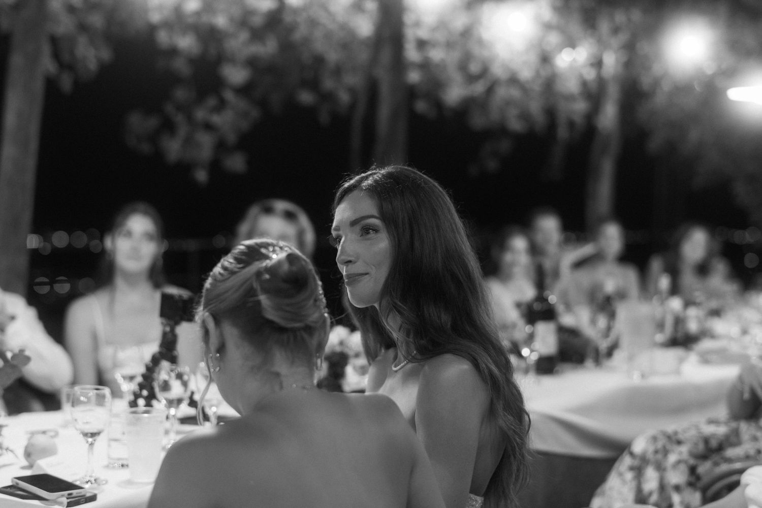 Black and white panoramic view of guests seated at an elegant wedding reception dinner table.