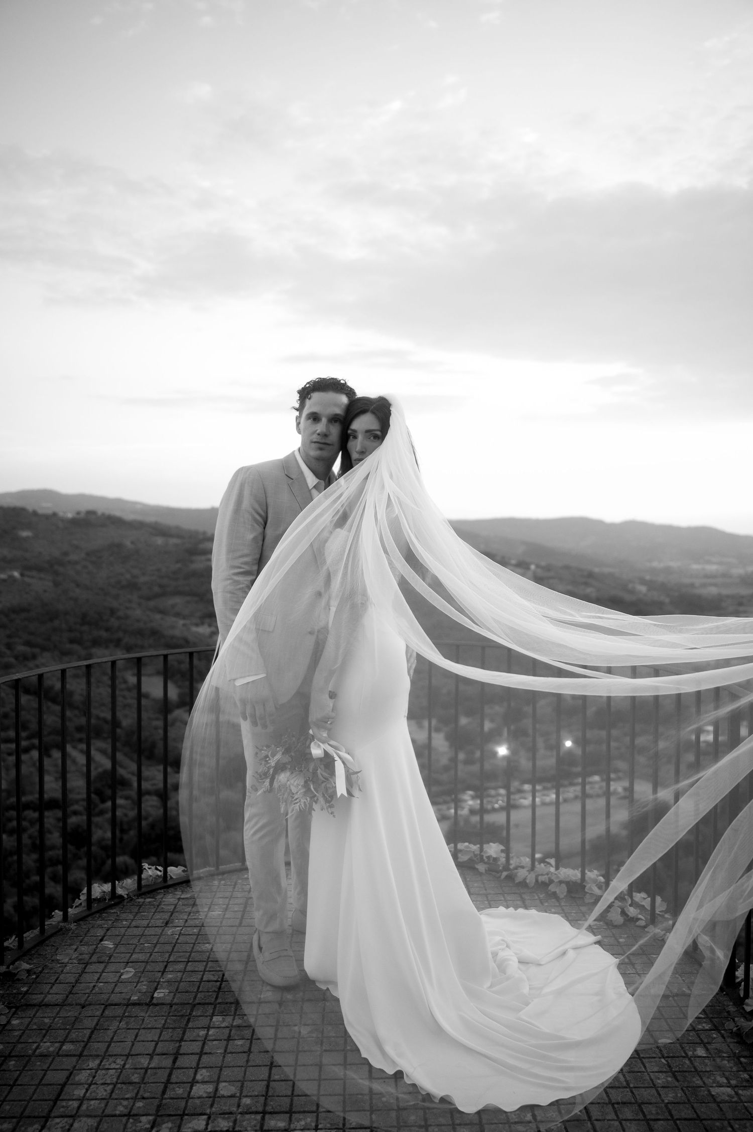 A romantic black and white wedding photo series showing a flowing veil caught in the wind against a mountain landscape.