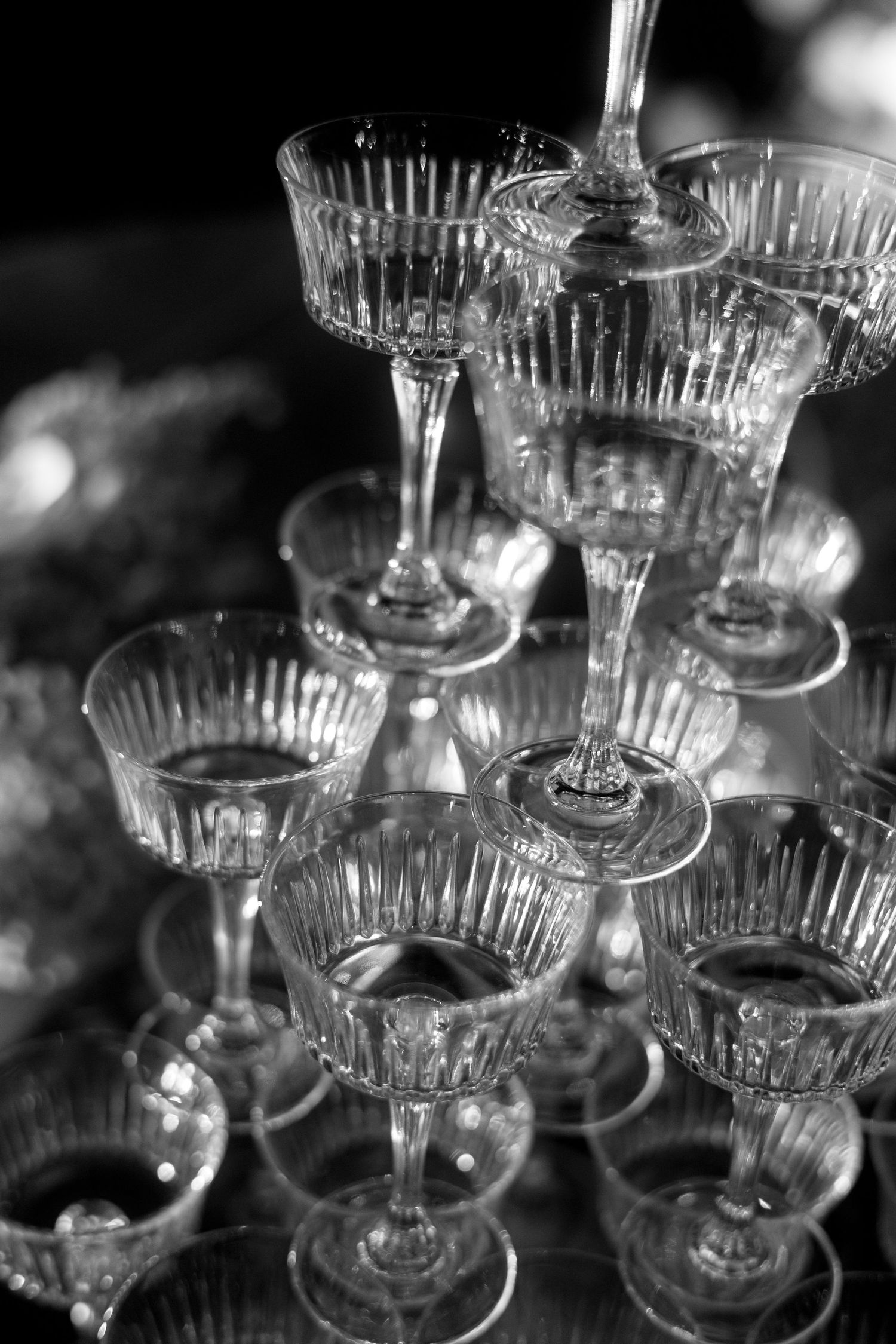 Elegant crystal champagne glasses stacked in a pyramid formation captured in black and white photography.