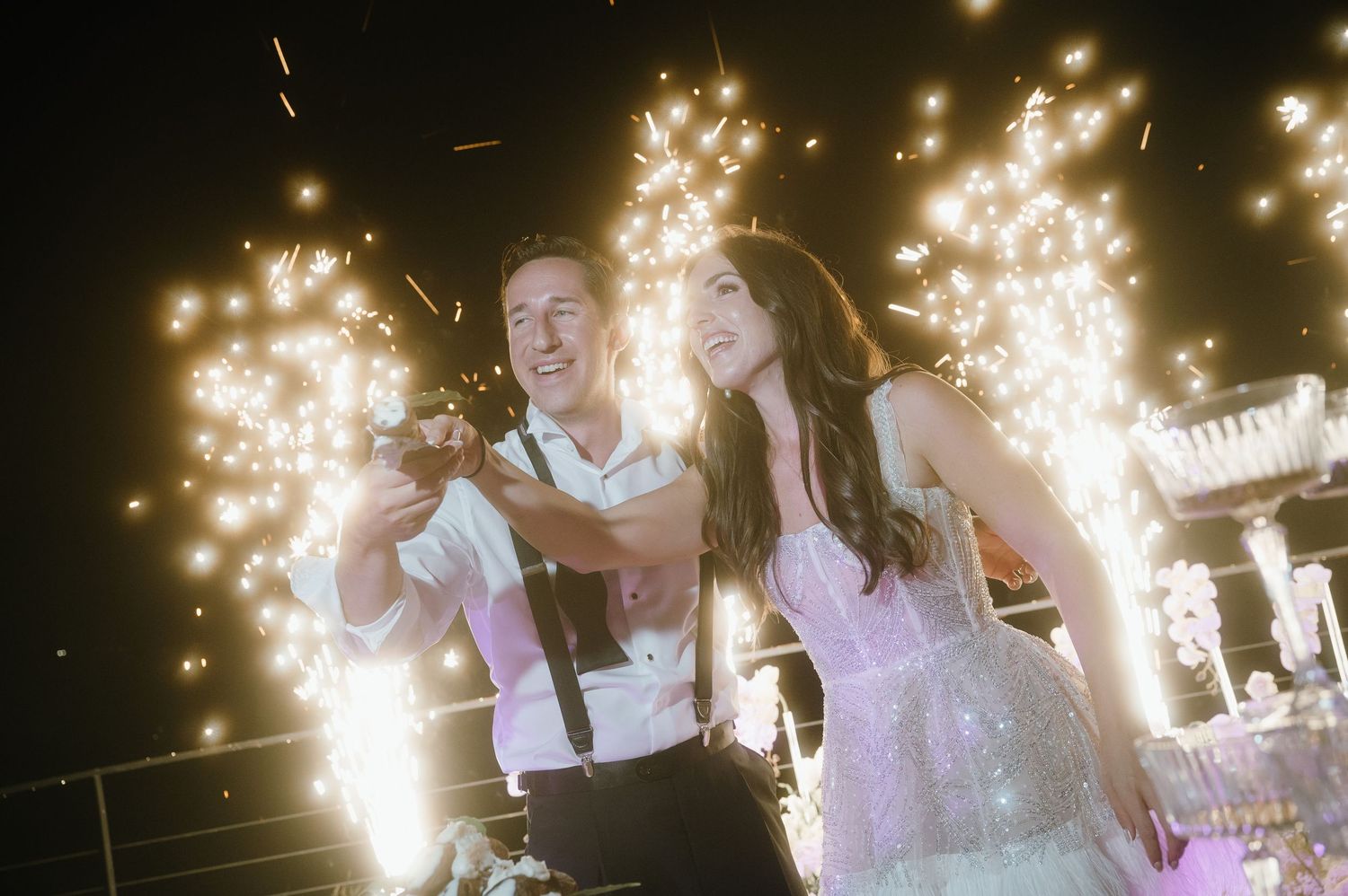 A couple dances together at a wedding reception with sparklers creating a magical backdrop of light and celebration.