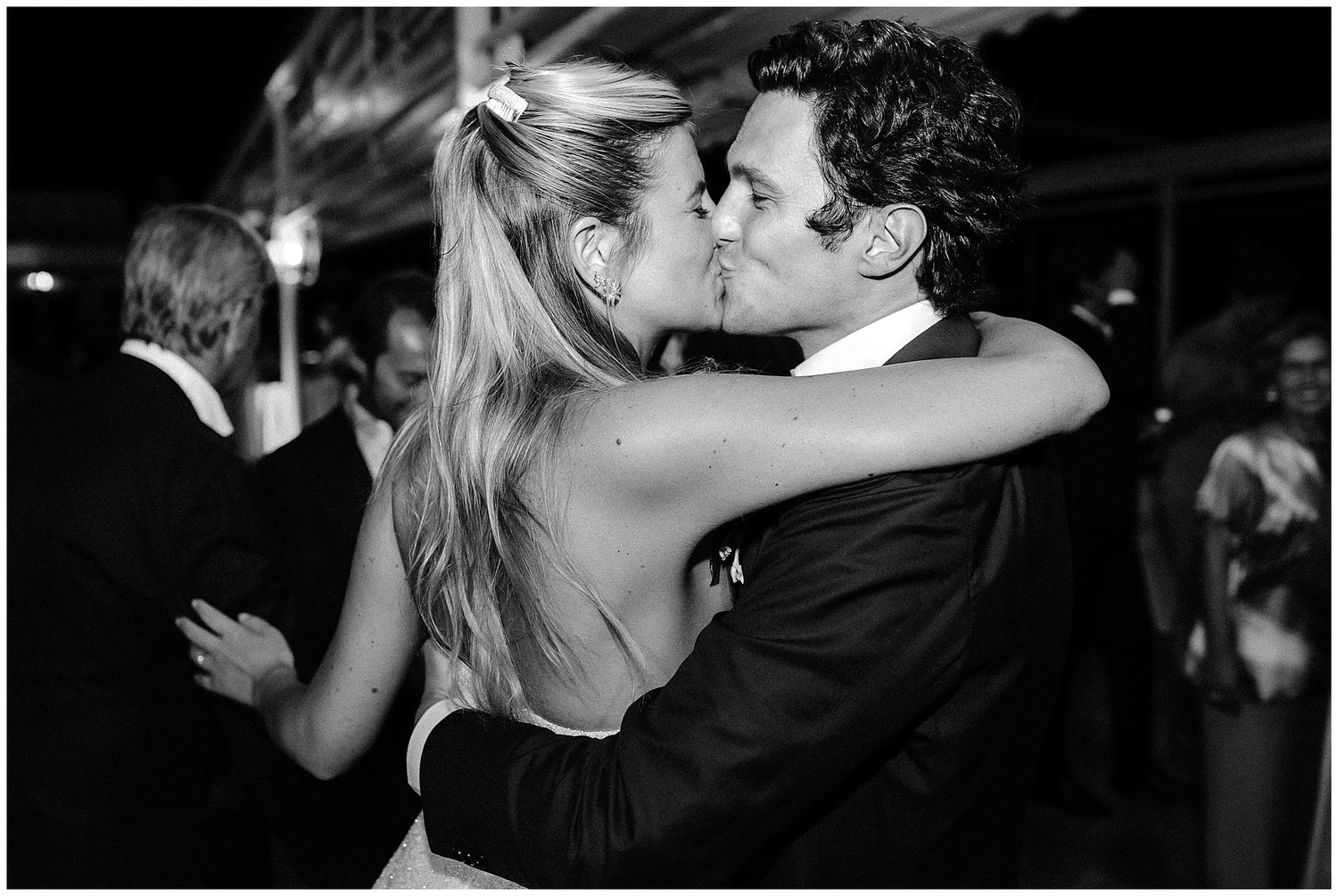 Black and white photograph capturing an intimate moment of a couple dancing closely at a formal event.
