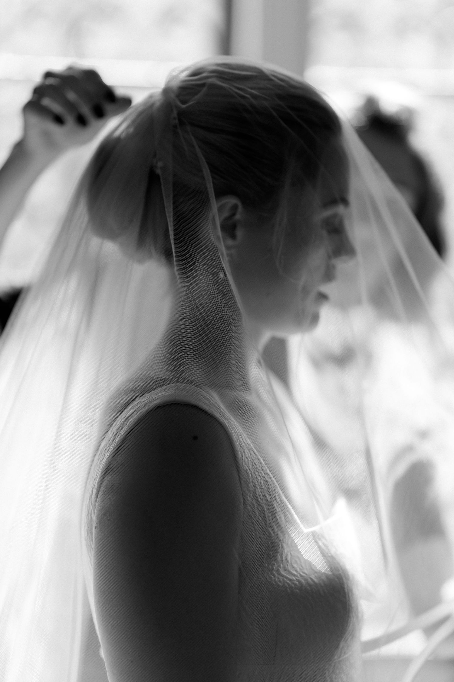 A soft, ethereal black and white photo series showing a bride's silhouette behind a delicate veil.