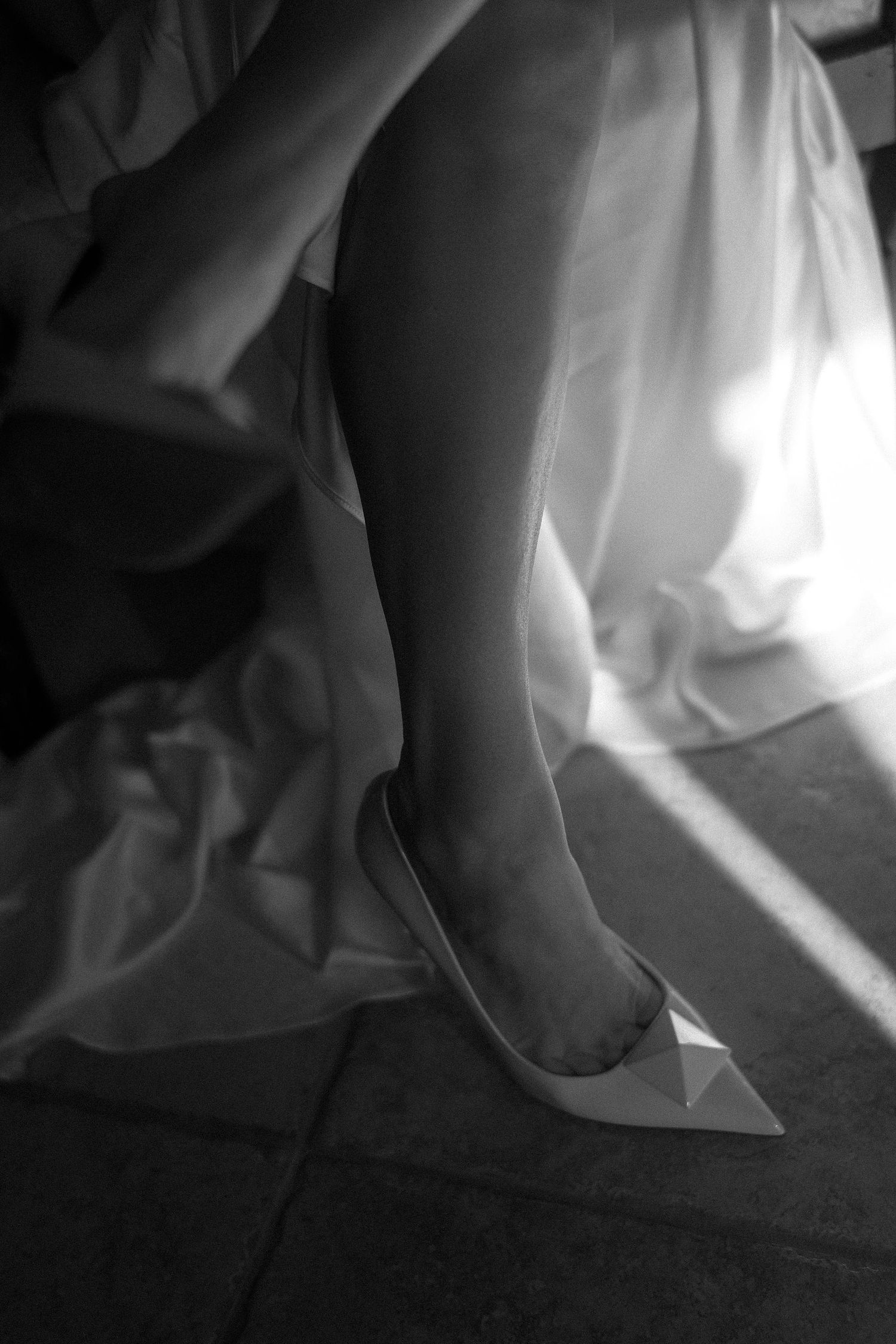 A sequence of black and white images showing a foot stepping on white fabric against a dark background.