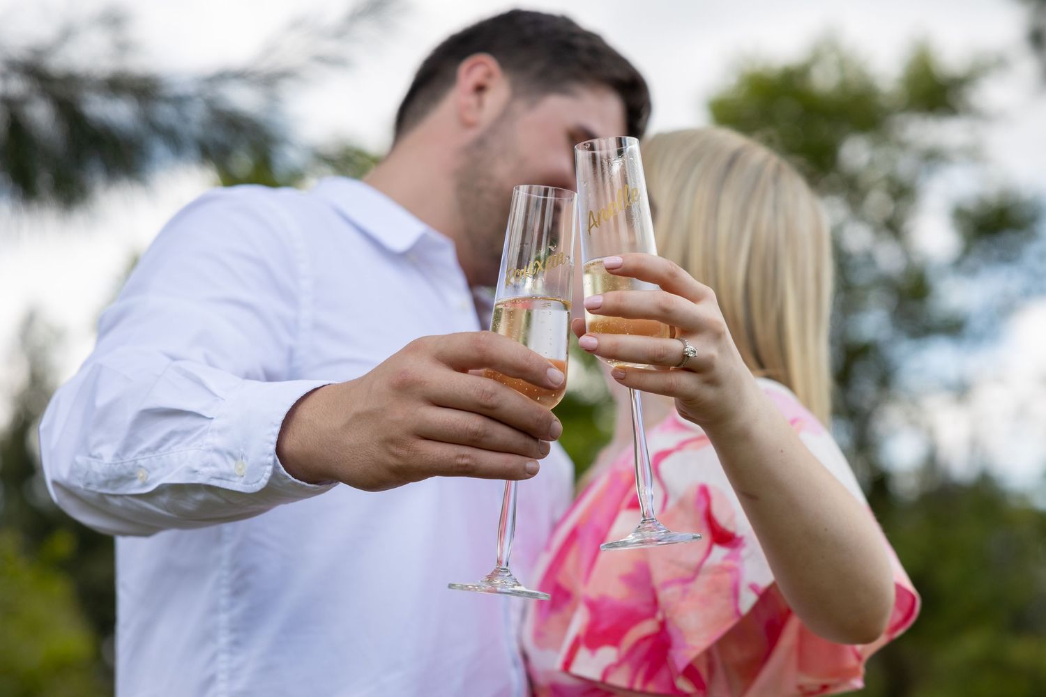 Couple celebrating with champagne glasses in an outdoor garden setting.