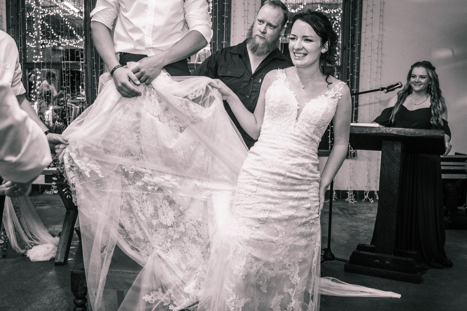 Bride laughing joyfully while dancing with groom at elegant wedding reception with live band.