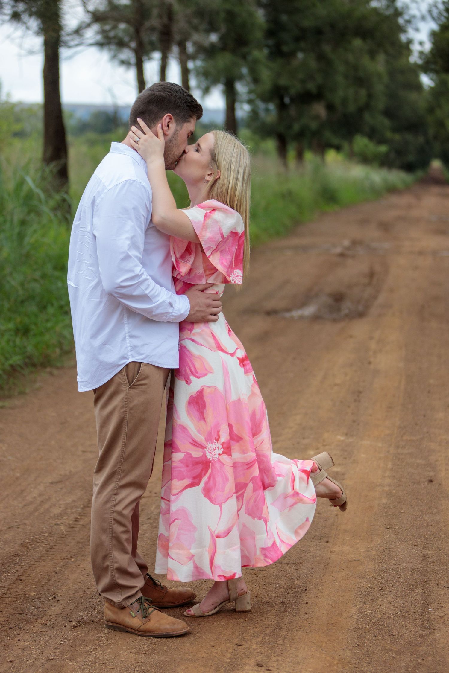 Couple sharing a romantic kiss on a scenic red dirt country road.