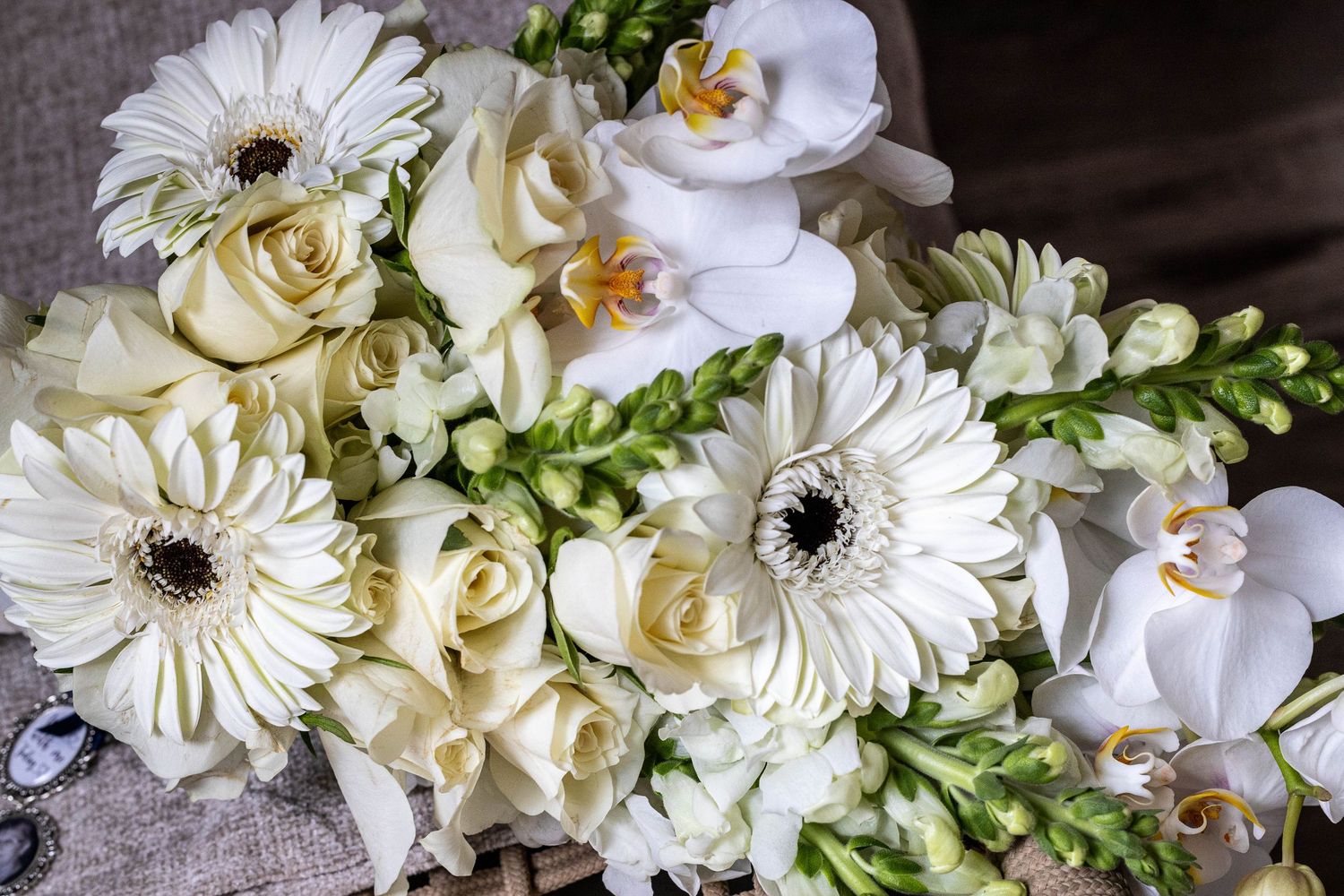 Bridal bouquet featuring white gerbera daisies, roses, freesia, and orchids arranged together.