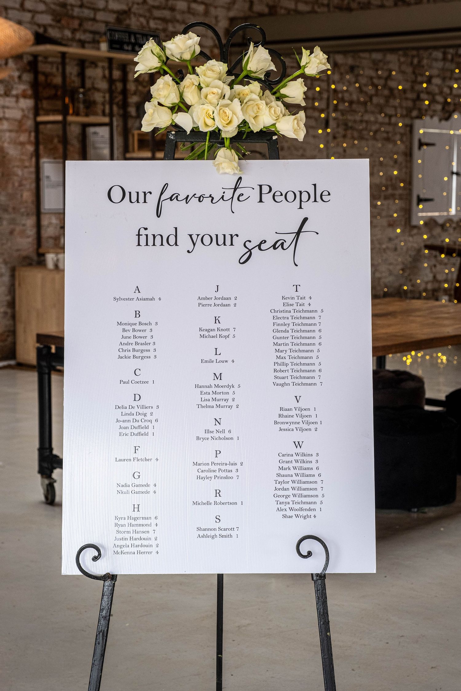Wedding seating chart sign reading Our Favorite People Find Your Seat with white rose arrangement.