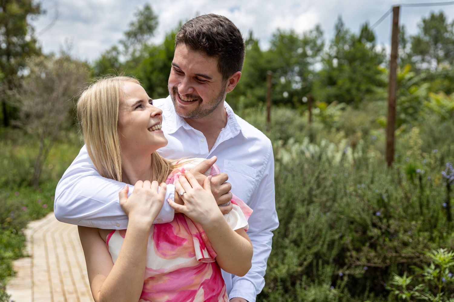 Happy couple embracing and smiling at each other in a lush green garden.