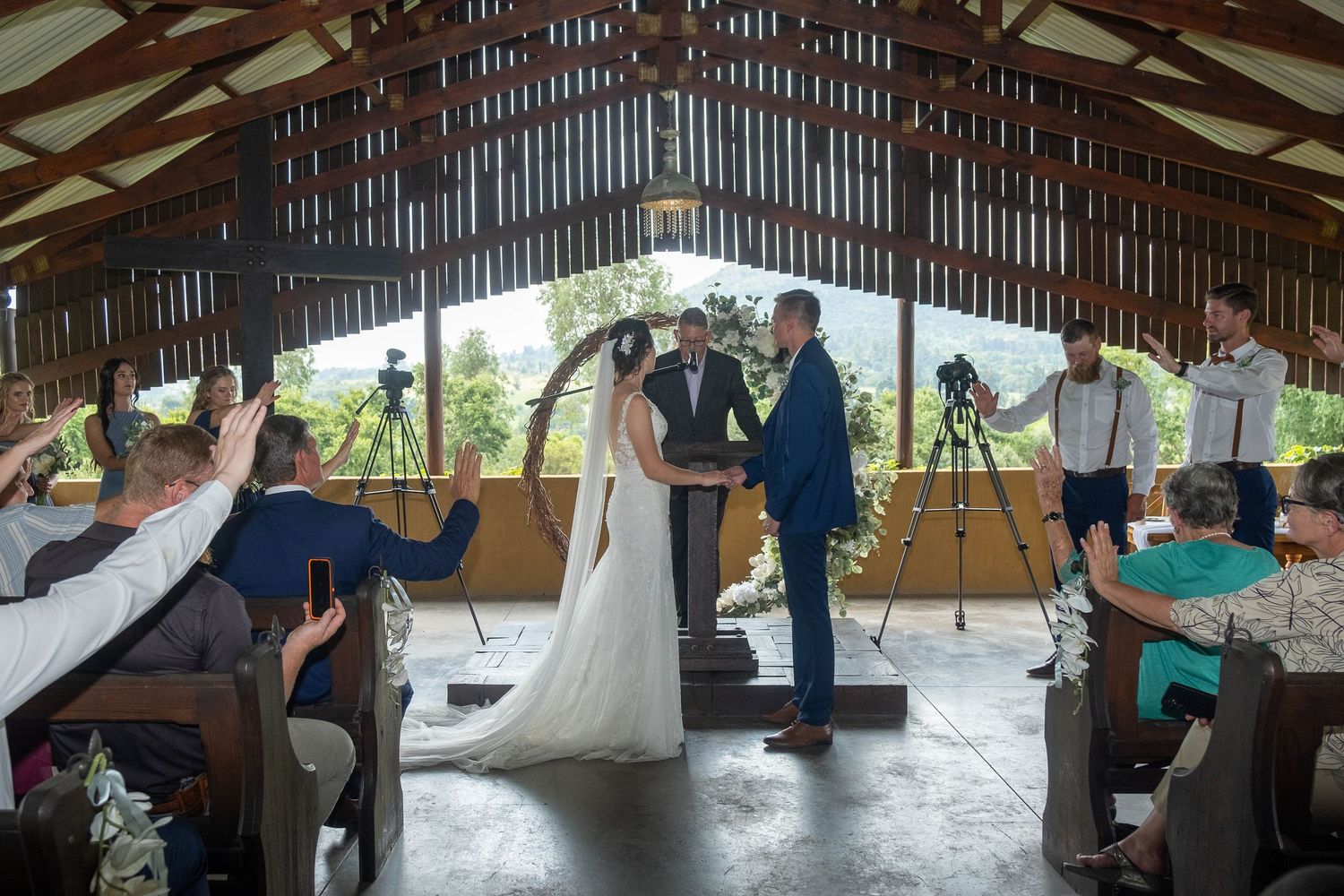 A bride and groom exchange vows at the altar in a rustic wooden chapel surrounded by wedding guests.