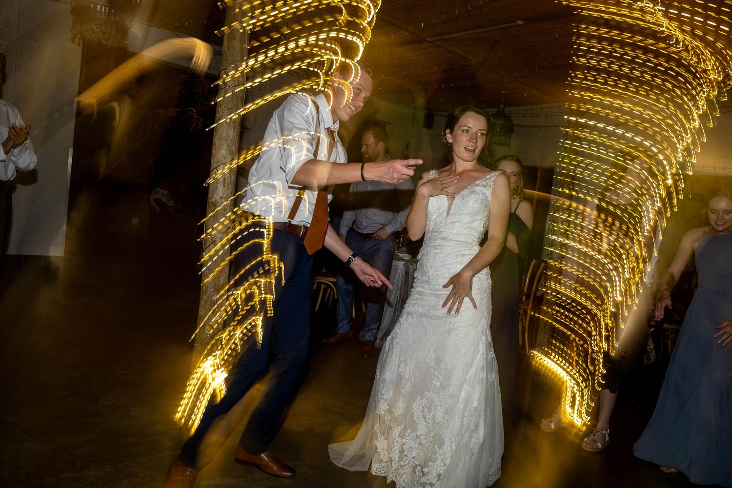 Bride and groom dancing together surrounded by swirling golden bokeh lights at reception.