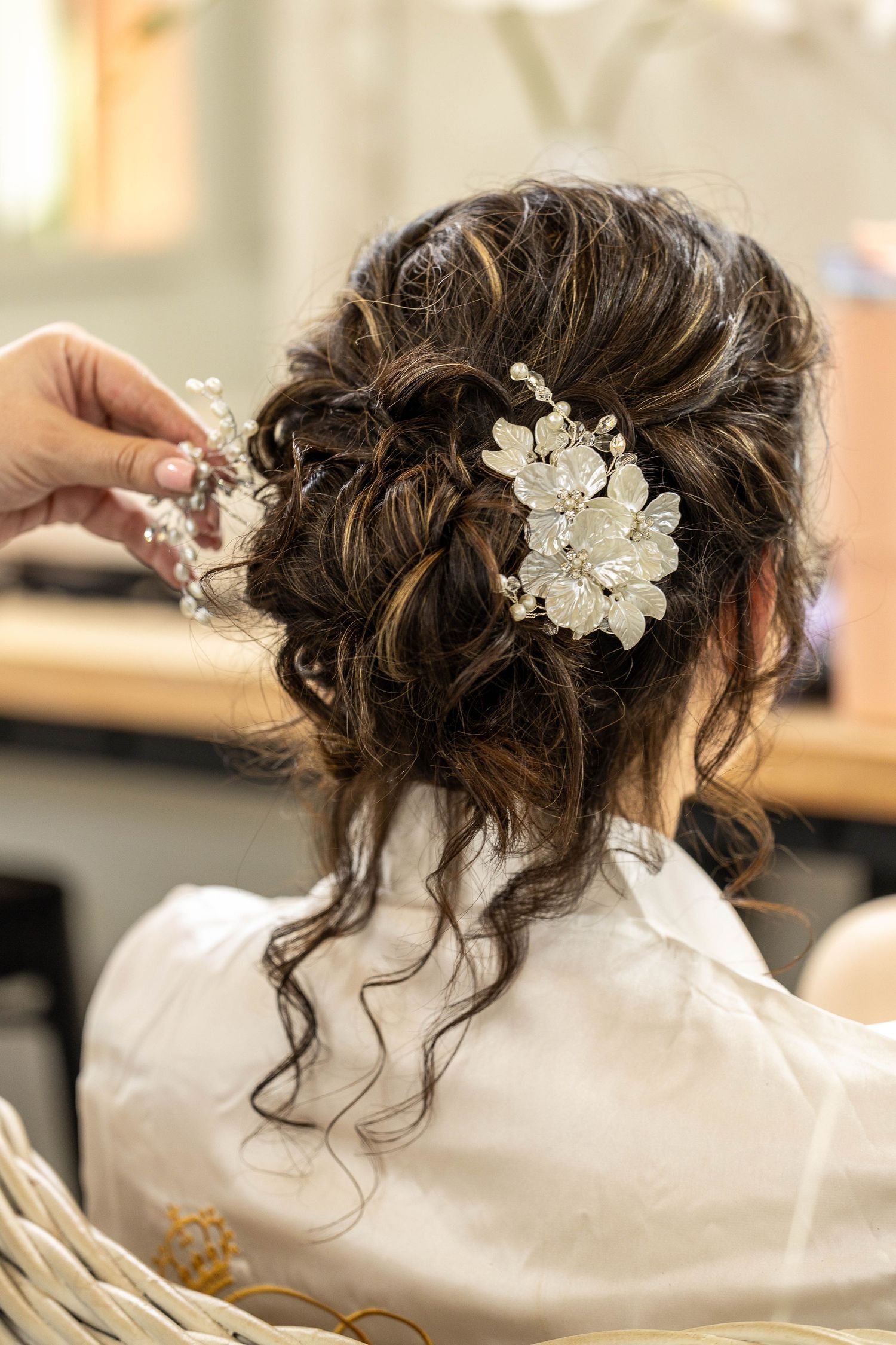 Close-up of bride's elegant updo hairstyle adorned with a floral pearl hair accessory on her wedding day.