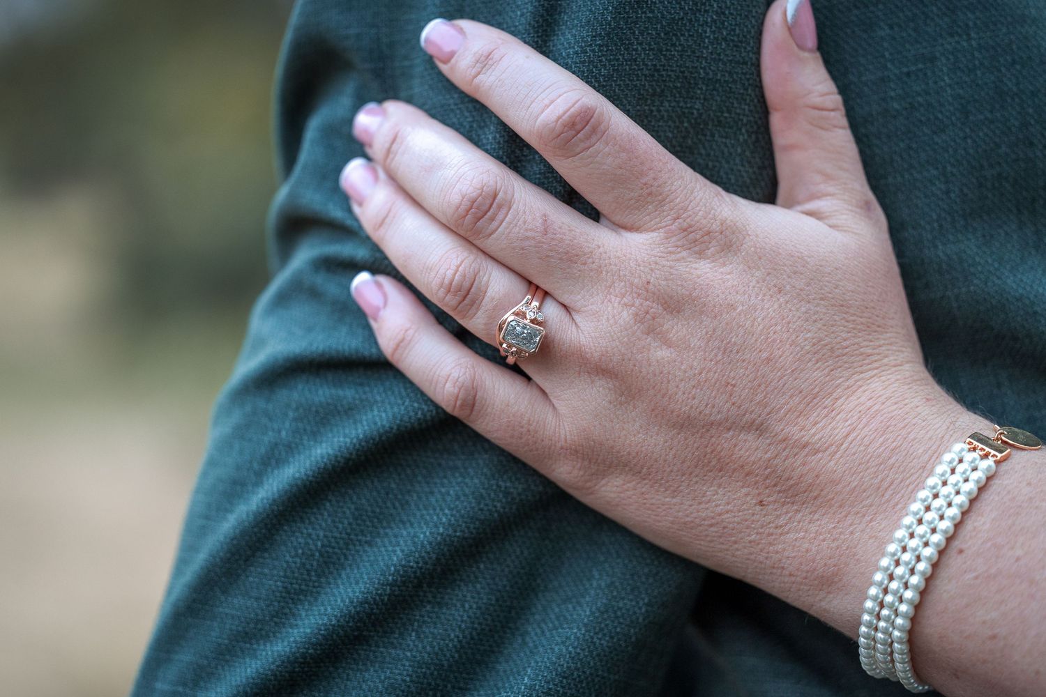 Close-up of bride's hand with diamond ring and pearl bracelet.