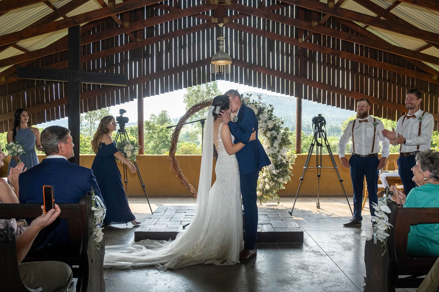 A bride and groom share their first kiss at the altar in a stunning rustic wooden wedding venue.