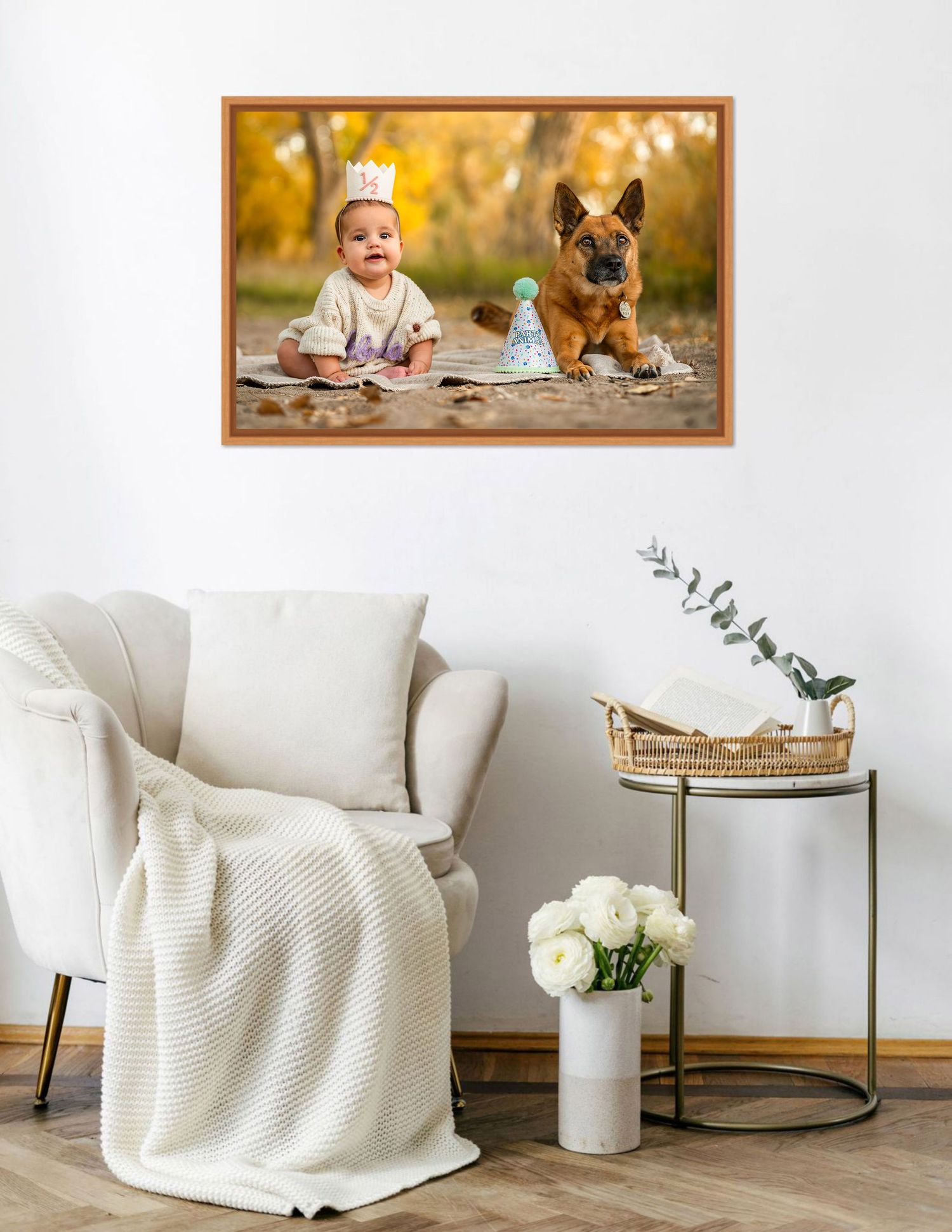 Framed photo of a baby and German Shepherd dog with party hats displayed above a white armchair in a cozy living room.
