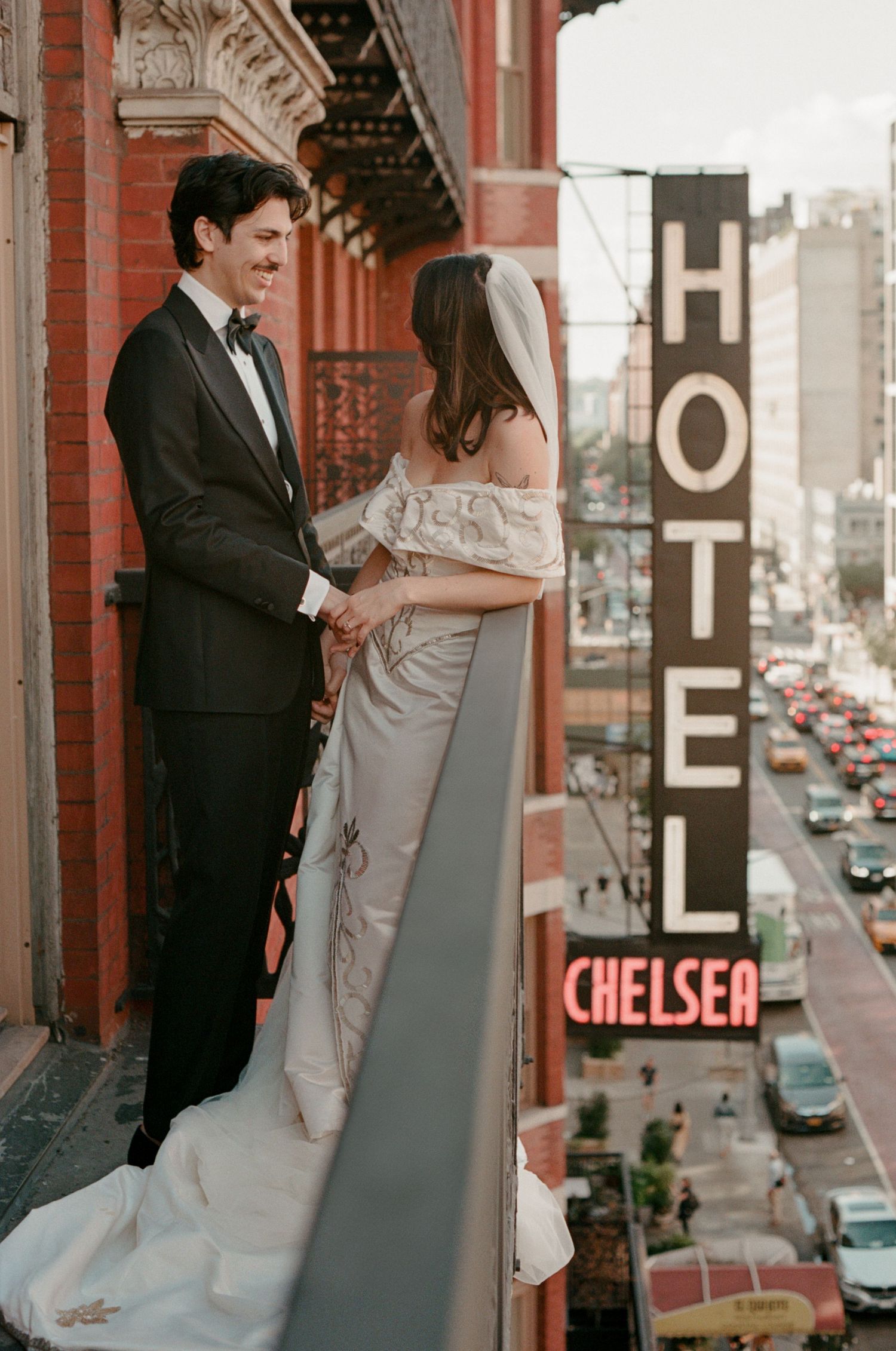 A wedding photoshoot on a balcony with Chelsea Hotel signage visible in background.