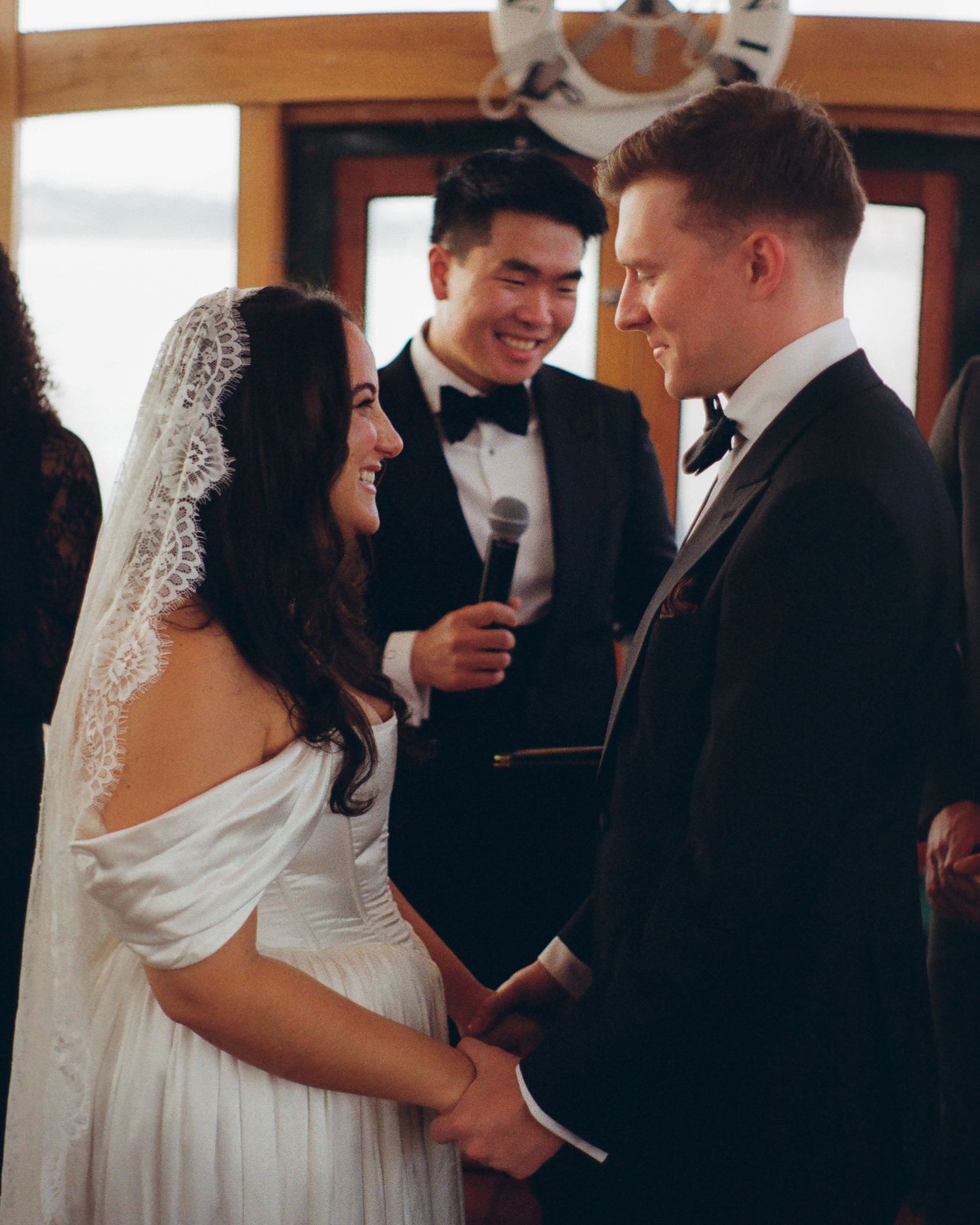 Wedding ceremony taking place inside a boat cabin with guests watching.