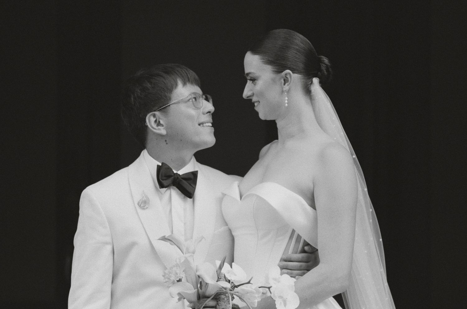 Classic black and white wedding portrait showing formal white attire and traditional styling.