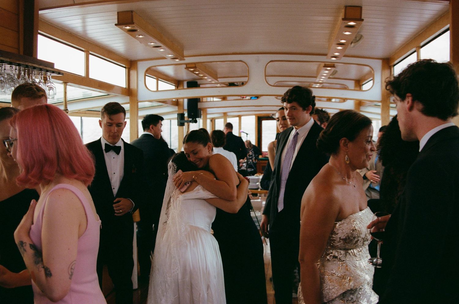 Wedding celebration aboard a boat with guests mingling in formal attire.