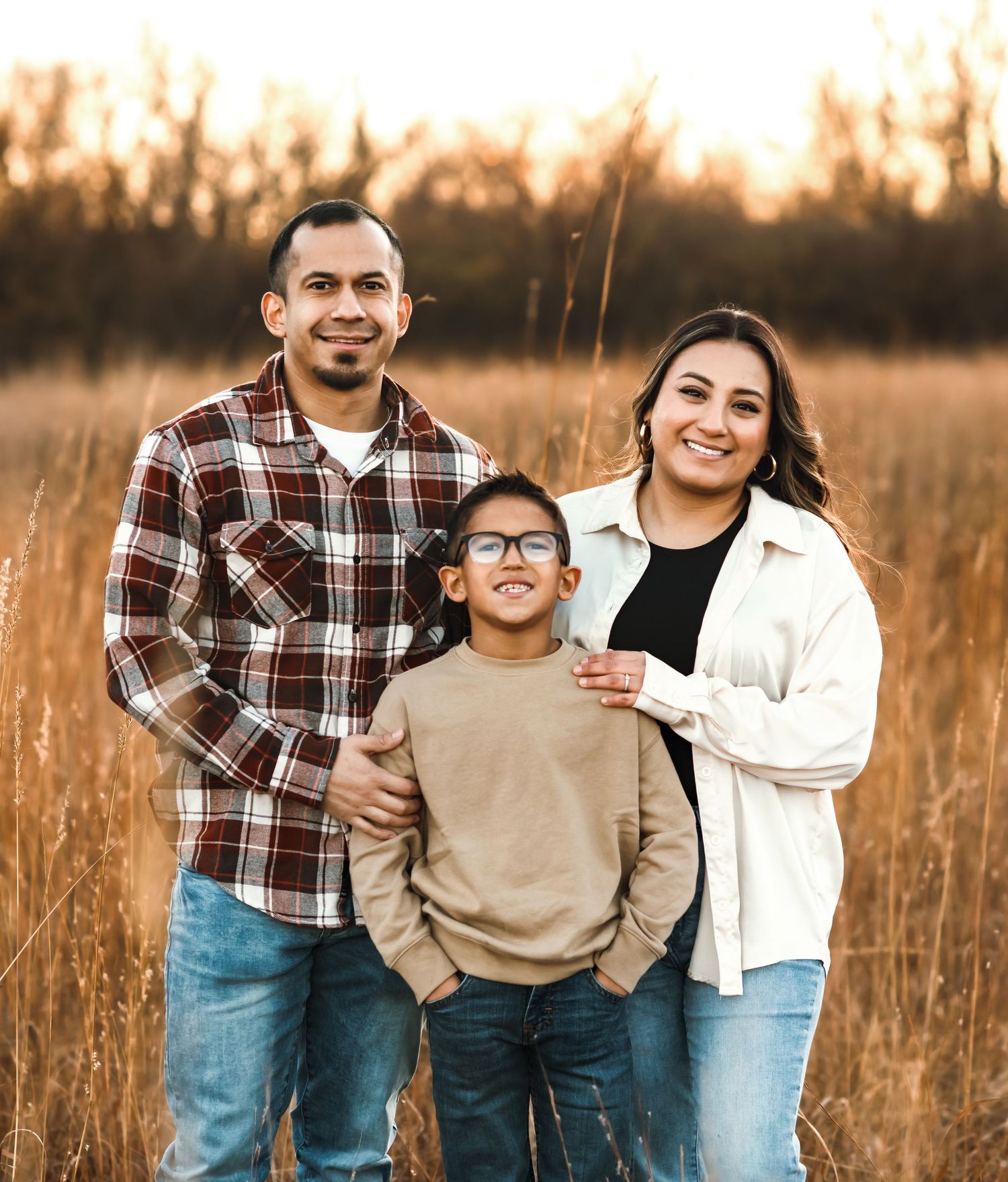 Family poses together in field during golden hour.