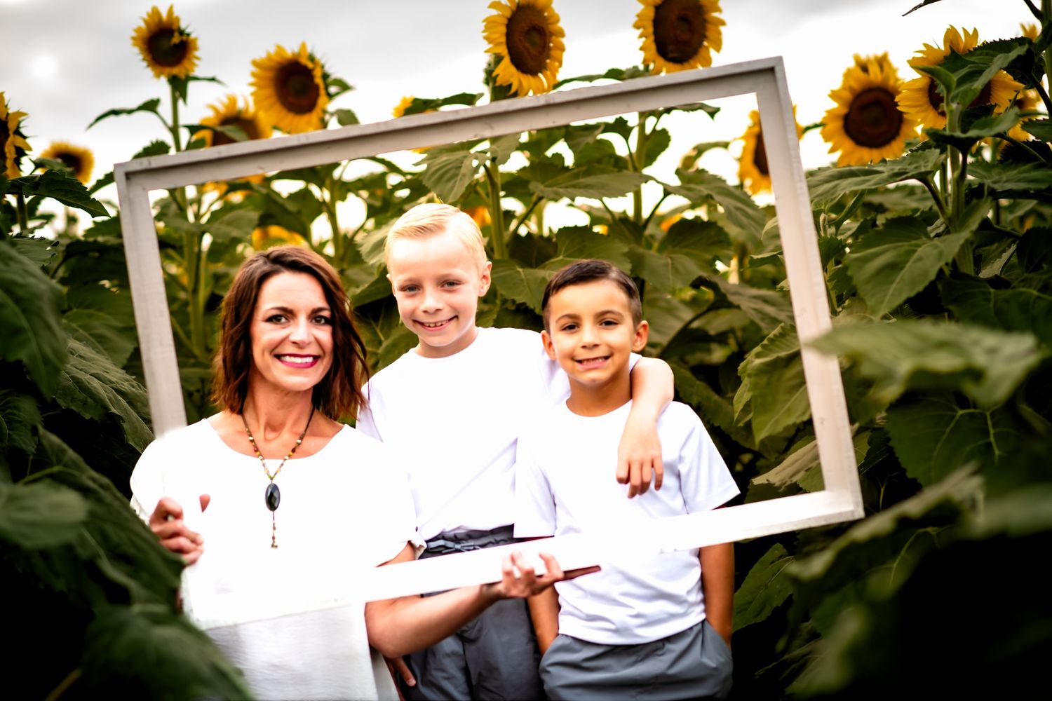 A joyful group poses together in a blooming sunflower field on a bright summer day.