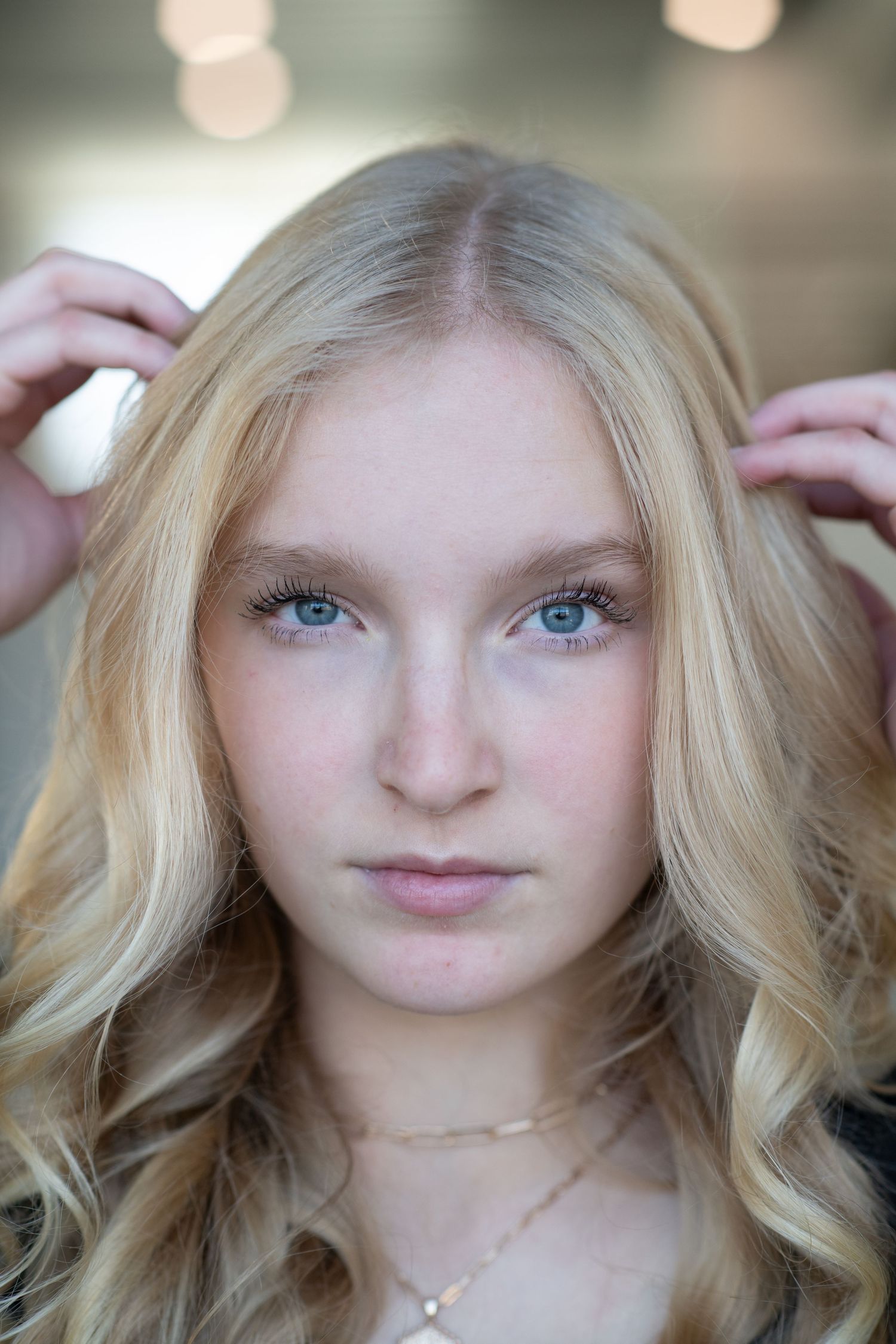 Close-up portrait with soft lighting of a person wearing delicate gold jewelry.
